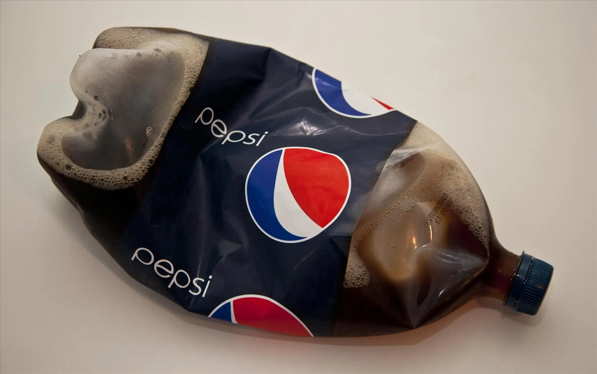 Crushed Pepsi bottle with soda spilling out.