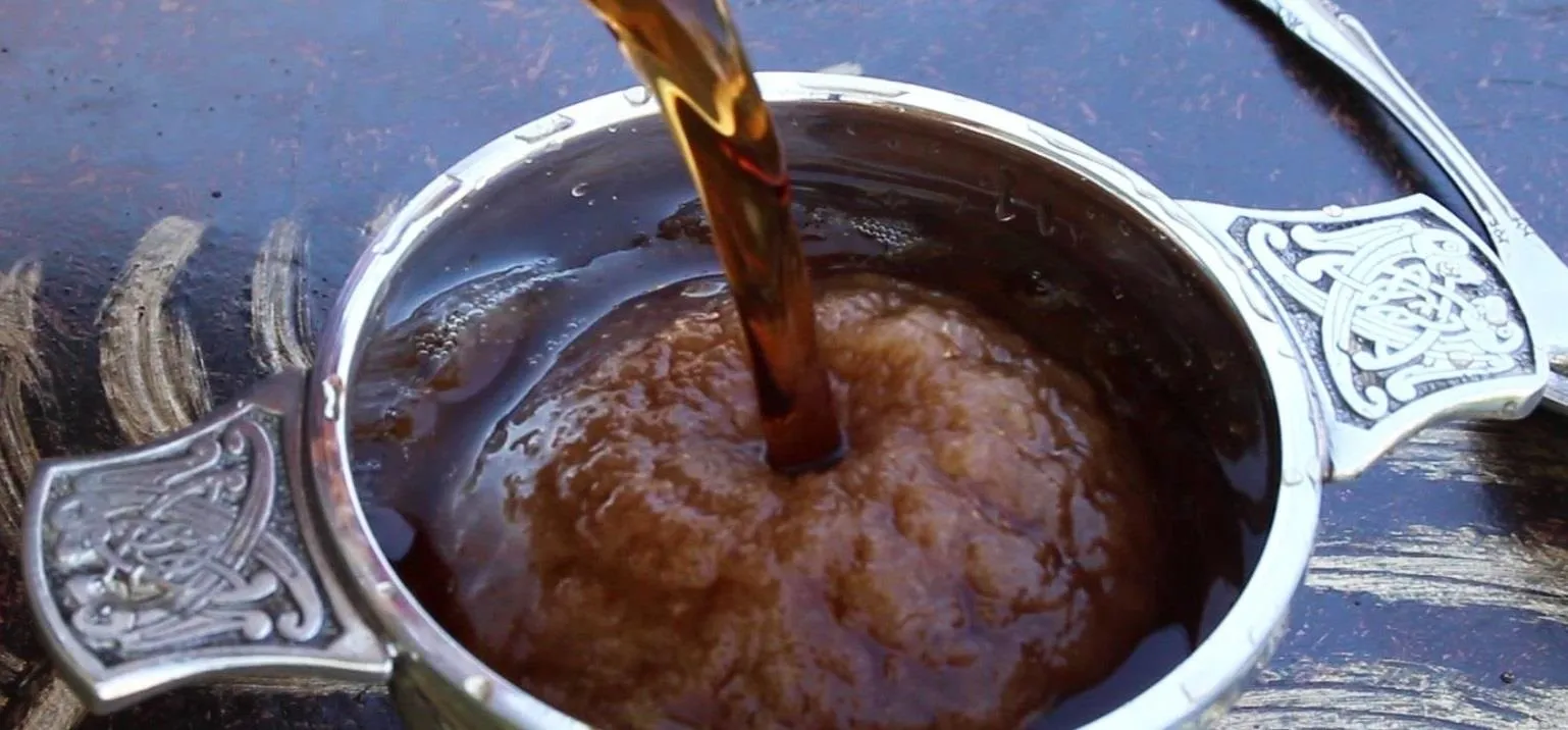 Freshly brewed tea being poured into a traditional silver cup.