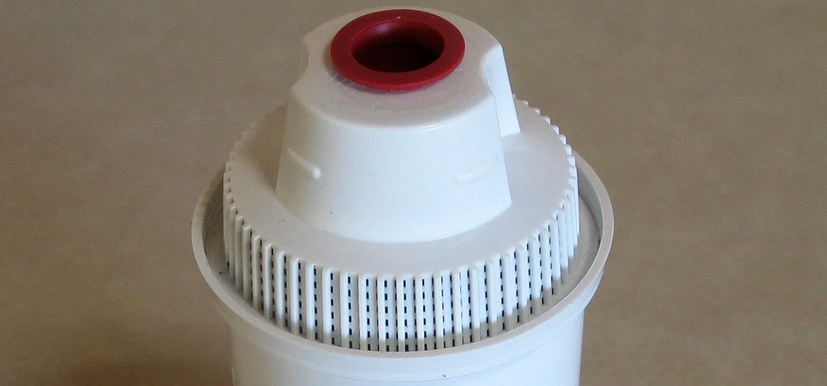 Water filter cartridge with a red top.
