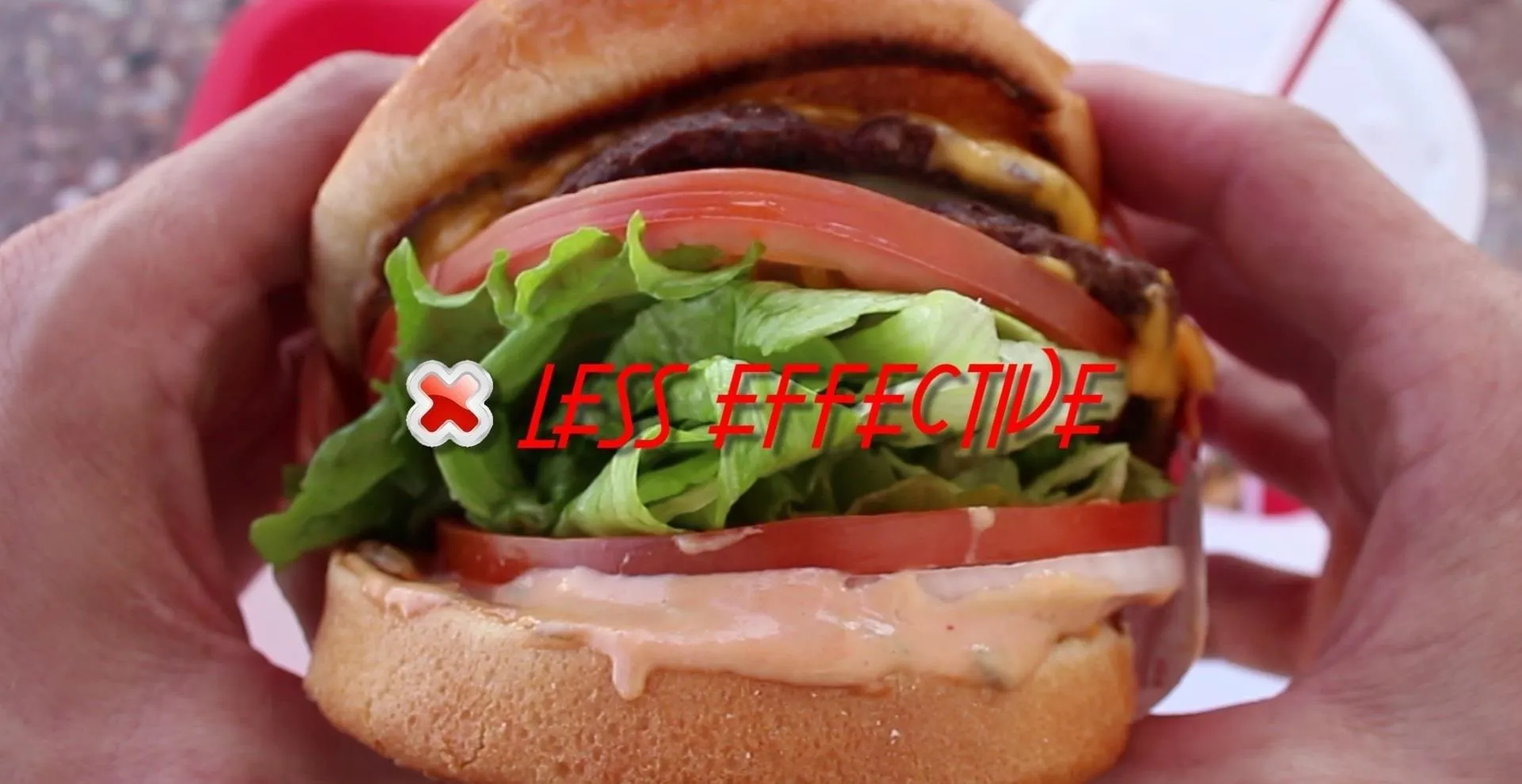 Cheeseburger with lettuce, tomato, and sauce held in hands.