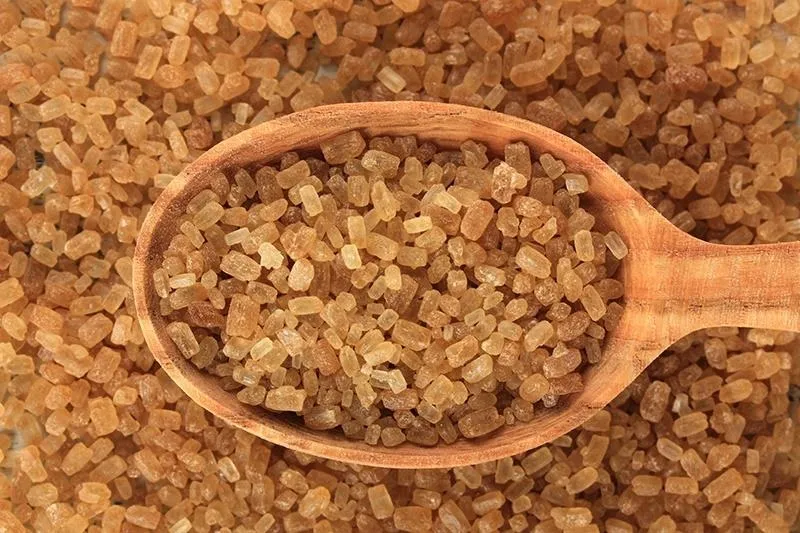 Brown sugar in a wooden spoon on a bed of brown sugar.