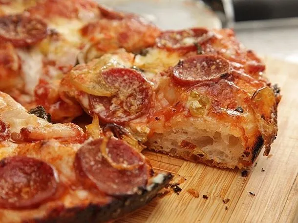 Pepperoni pizza on a wooden cutting board.
