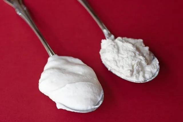 Spoons with whipped cream and powdered sugar on a red background