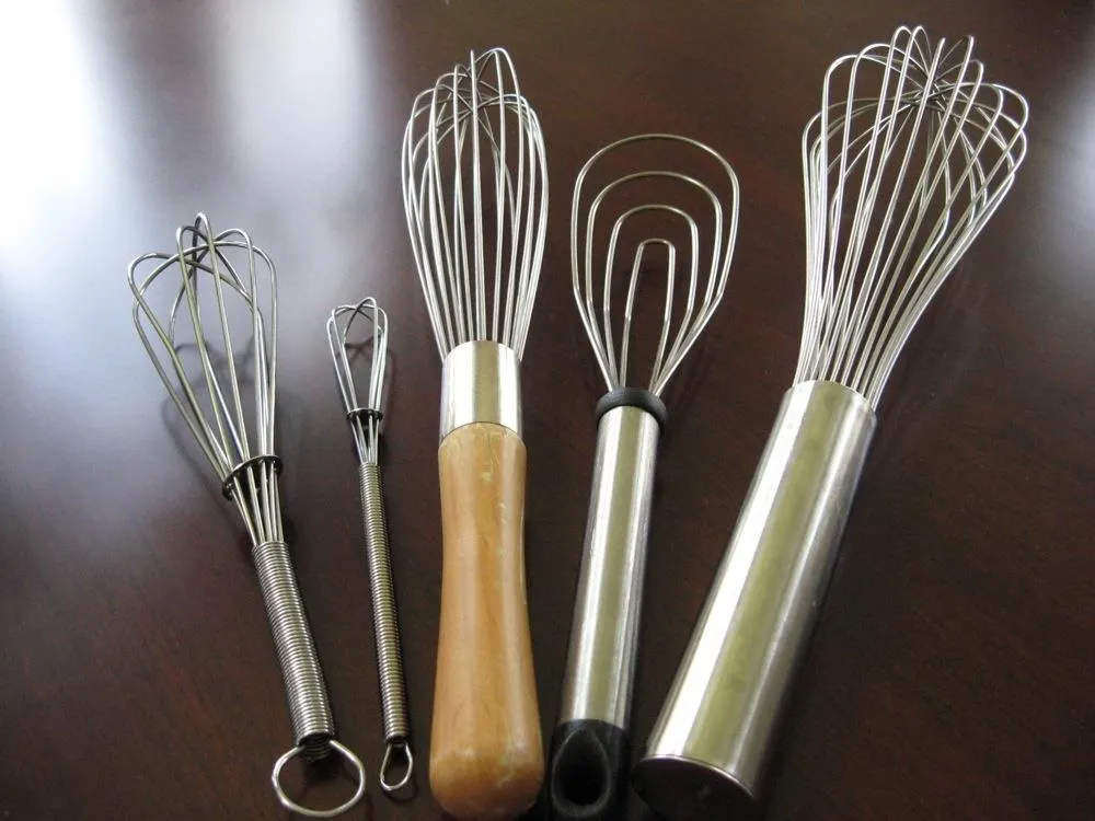 A variety of kitchen whisks in different sizes and styles.