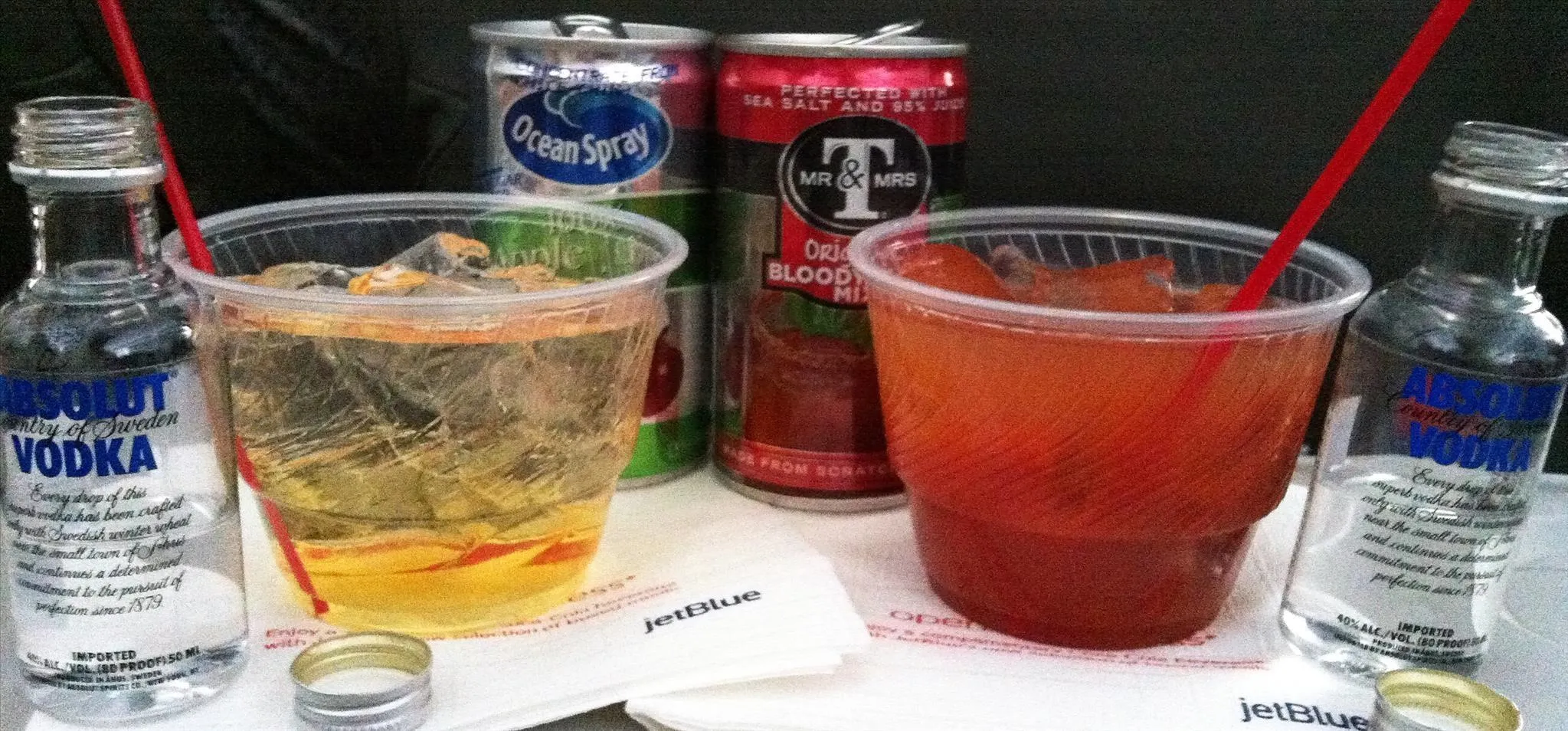 Beverages including vodka and mixed drinks in plastic cups with straws.
