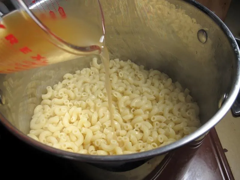 Cooking macaroni with broth in a pot.
