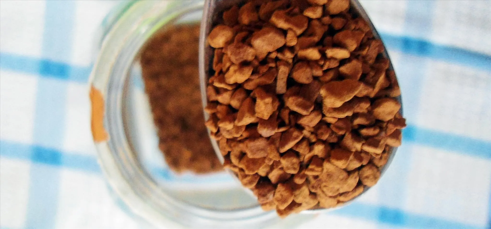 Spoonful of granules above a jar.