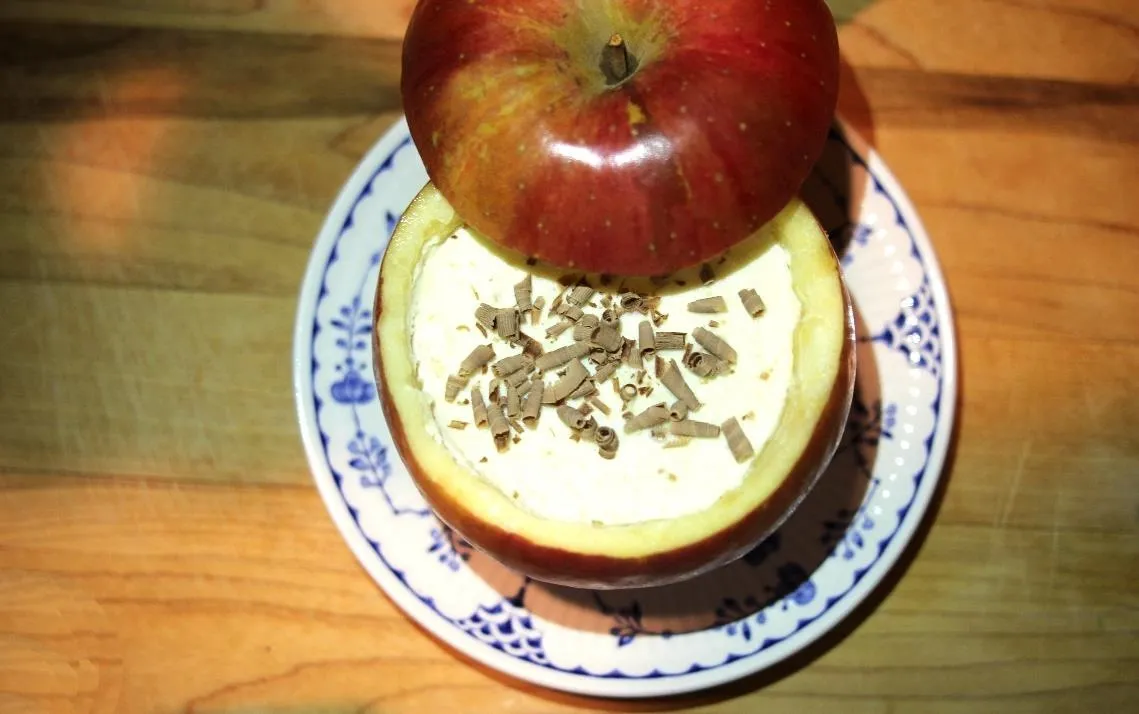 Apple dessert with cream and chocolate shavings on a decorative plate.