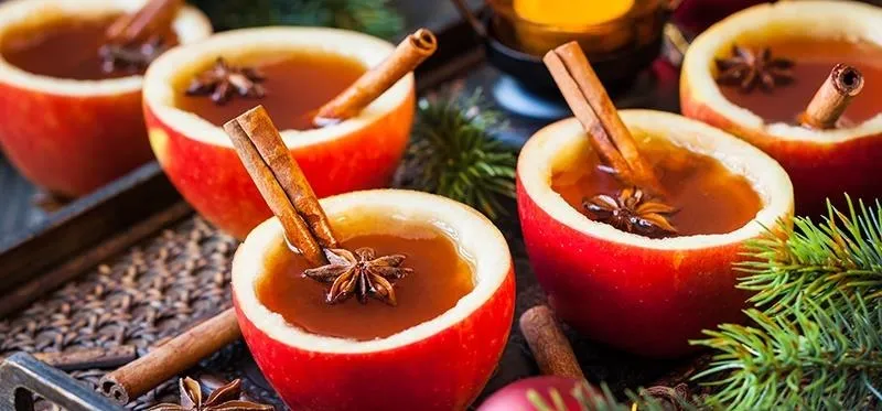 Spiced apple drinks served in hollowed-out apples with cinnamon and star anise.