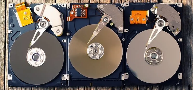 Three internal hard drives mounted on a wooden surface.