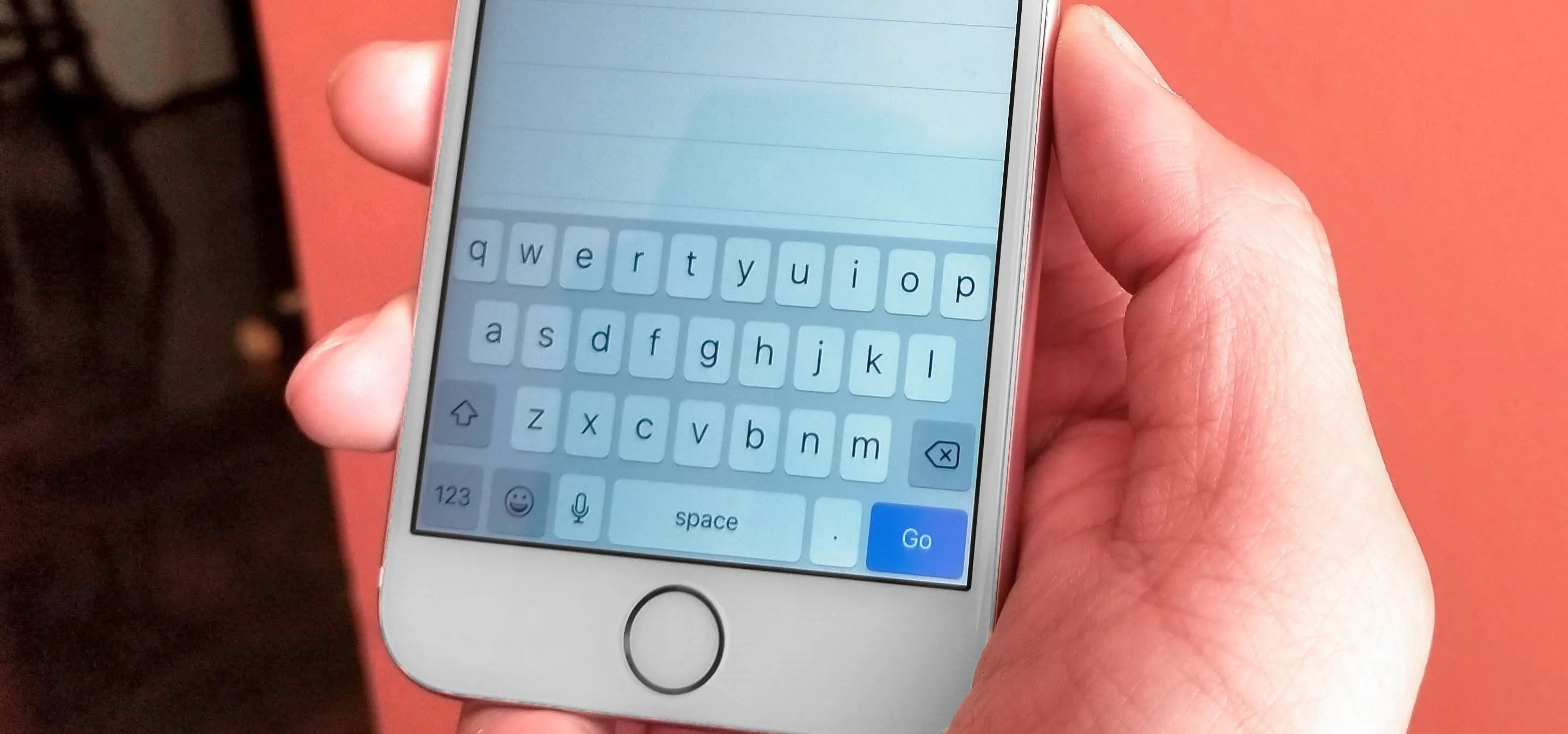 Person holding a smartphone displaying a text input screen.