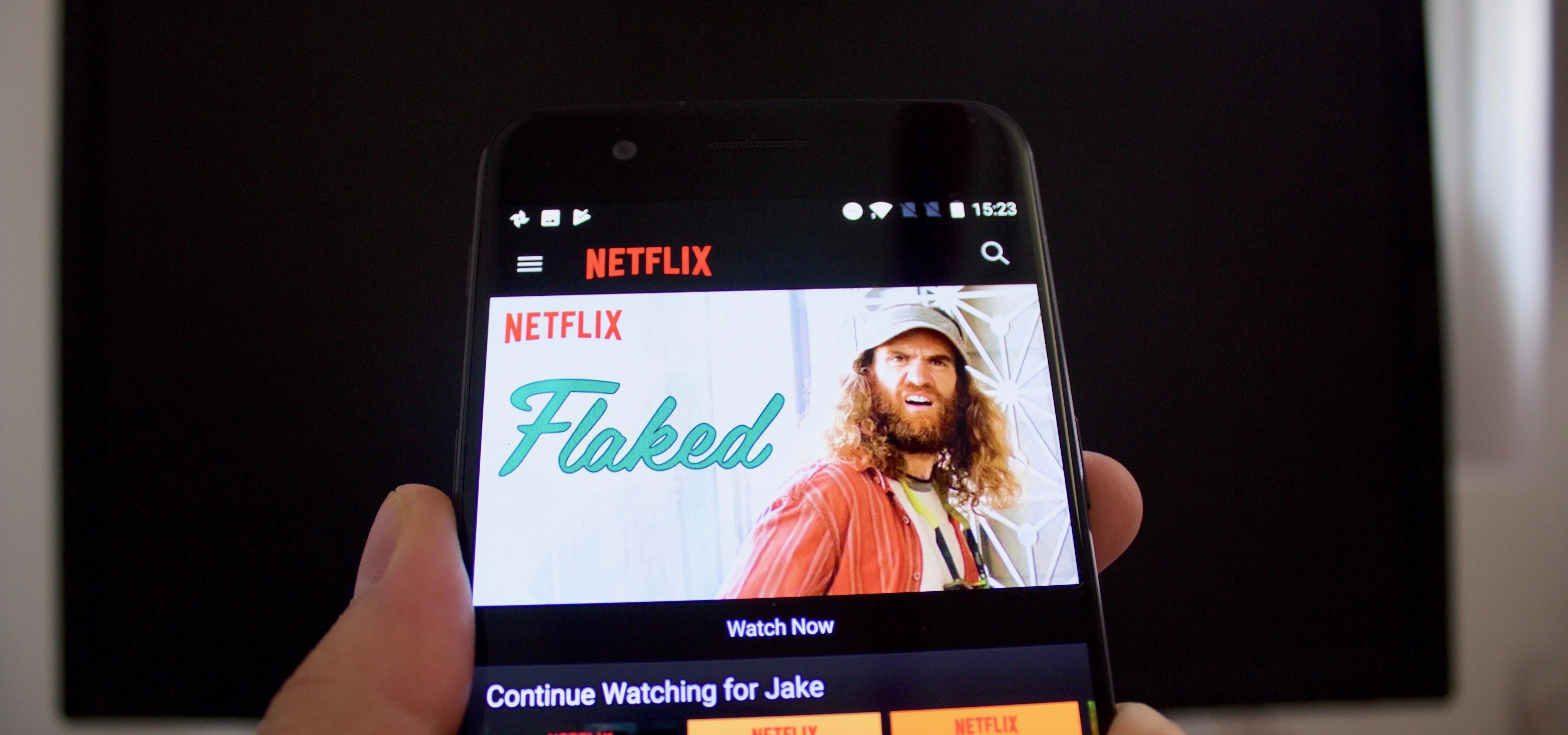 Person holding a smartphone displaying the Netflix "Flaked" series homepage.