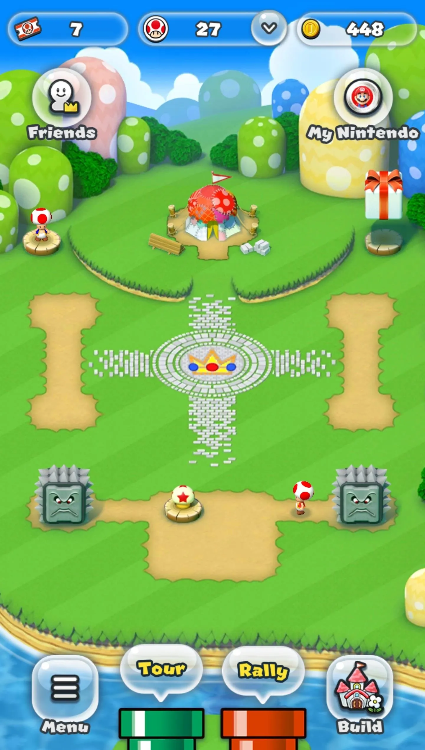 A colorful mobile game interface featuring a whimsical landscape with a central area and various interactive elements.