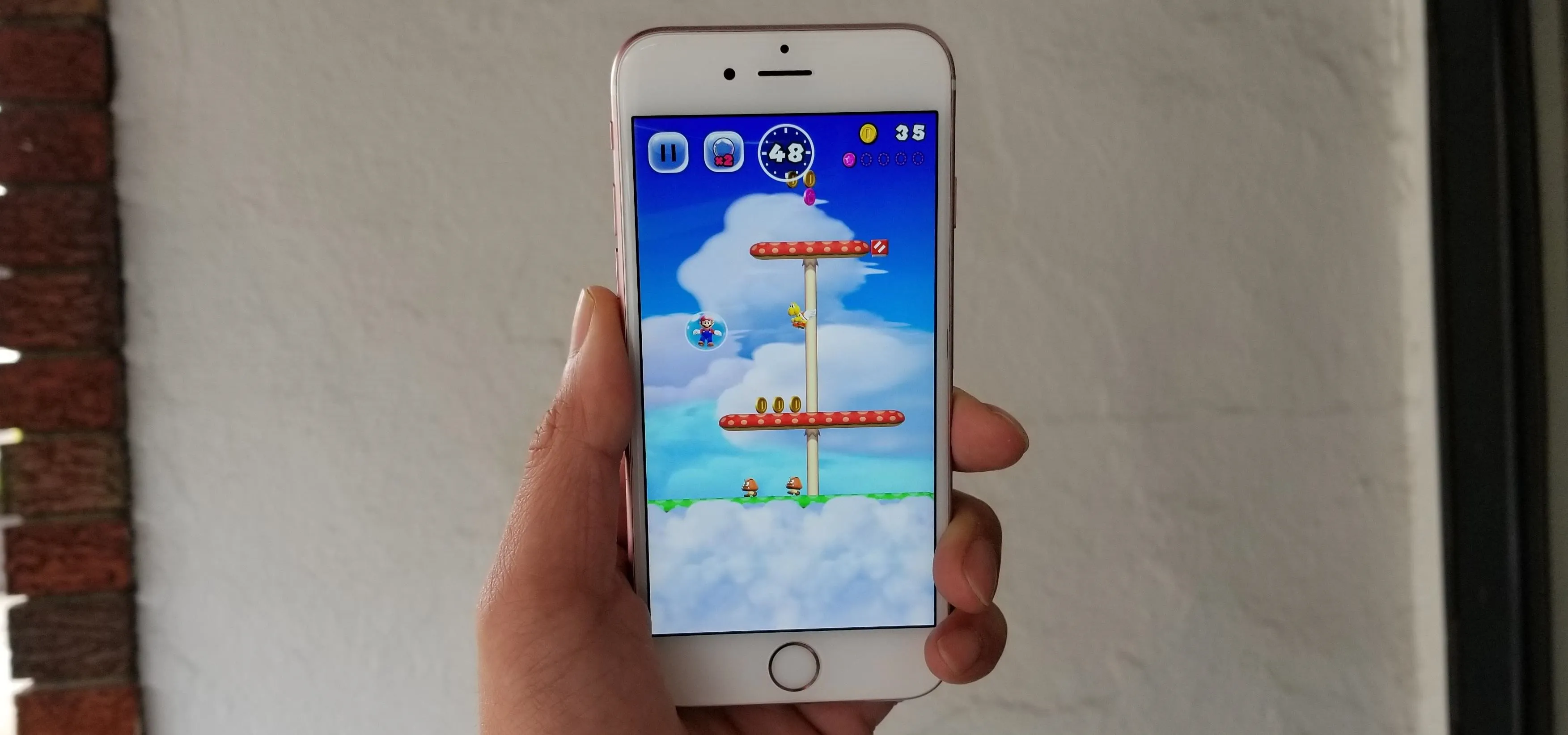 Hand holding a smartphone displaying a mobile game on its screen.