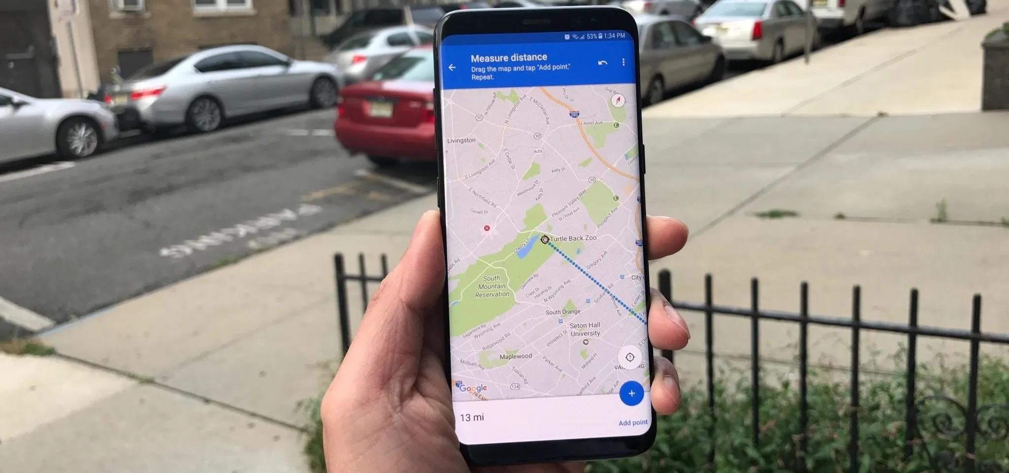 A hand holding a smartphone displaying a map with a marked location.