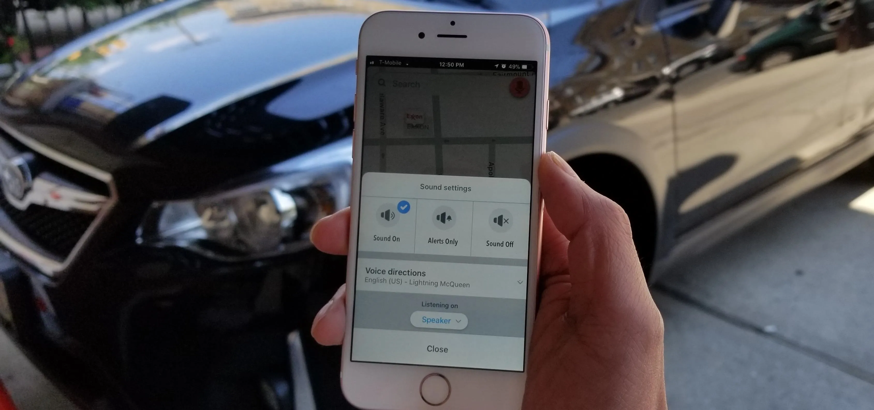 Person holding a smartphone with navigation app open next to a parked car.