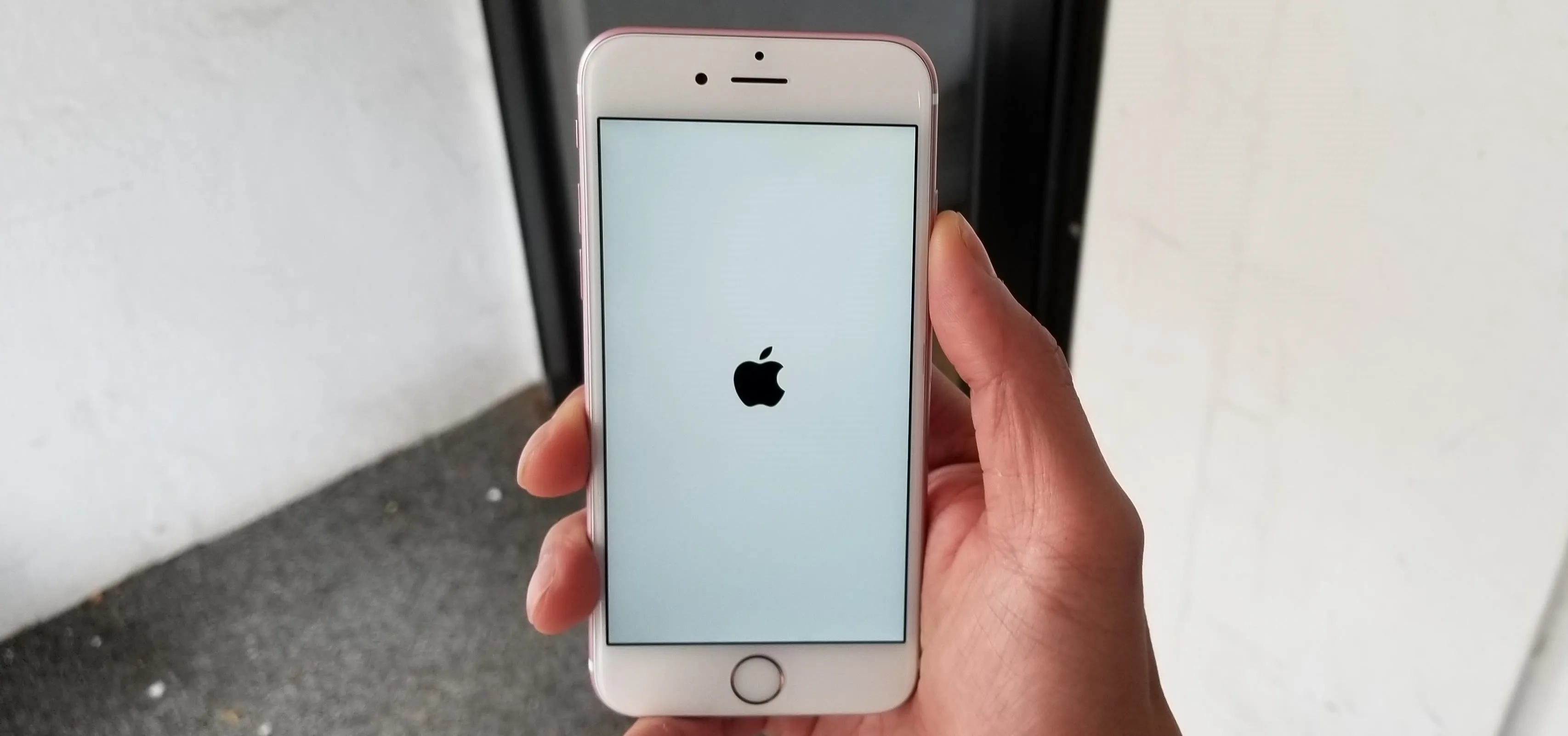 Hand holding a smartphone displaying the Apple logo on the screen.