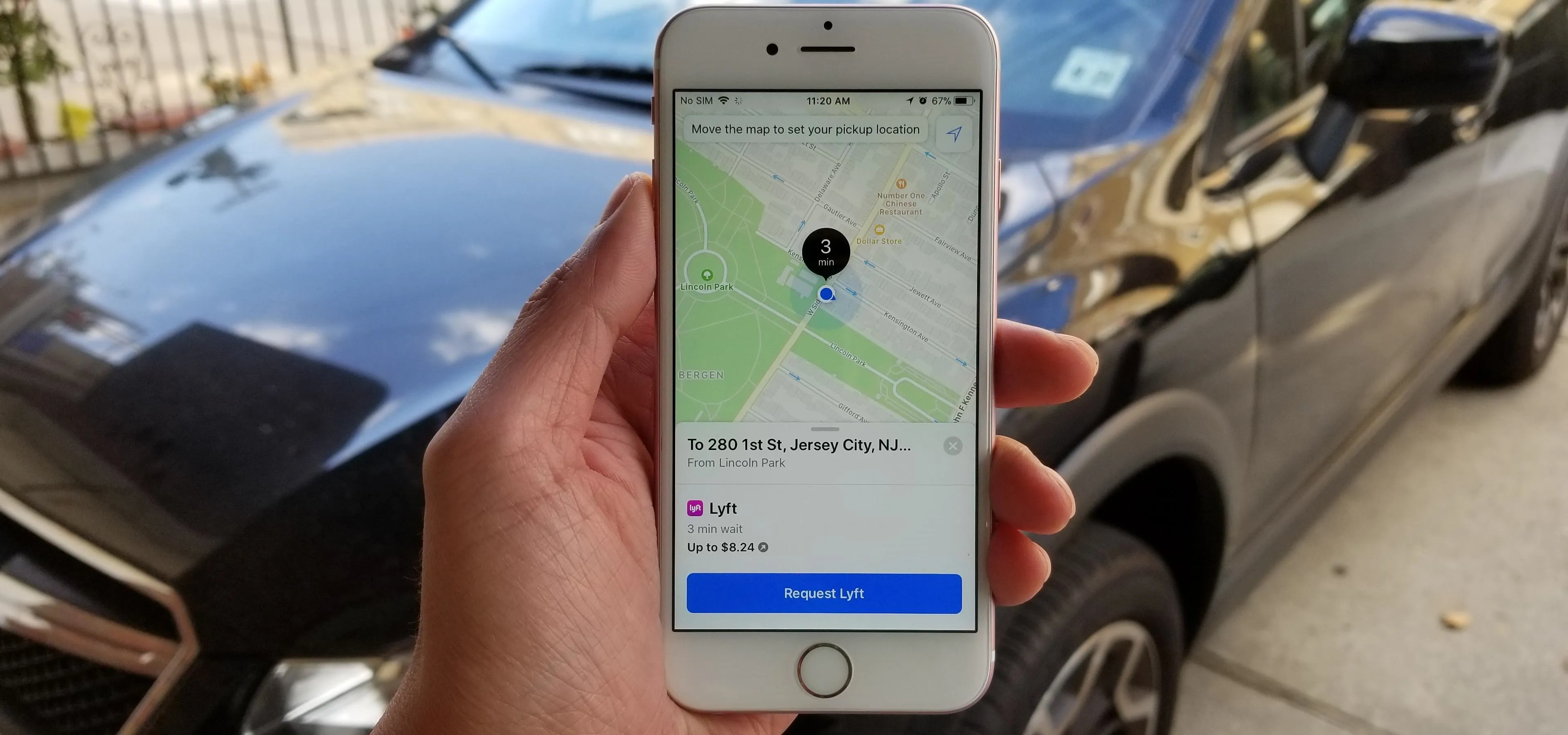 Person using a smartphone to view a map near a parked car.