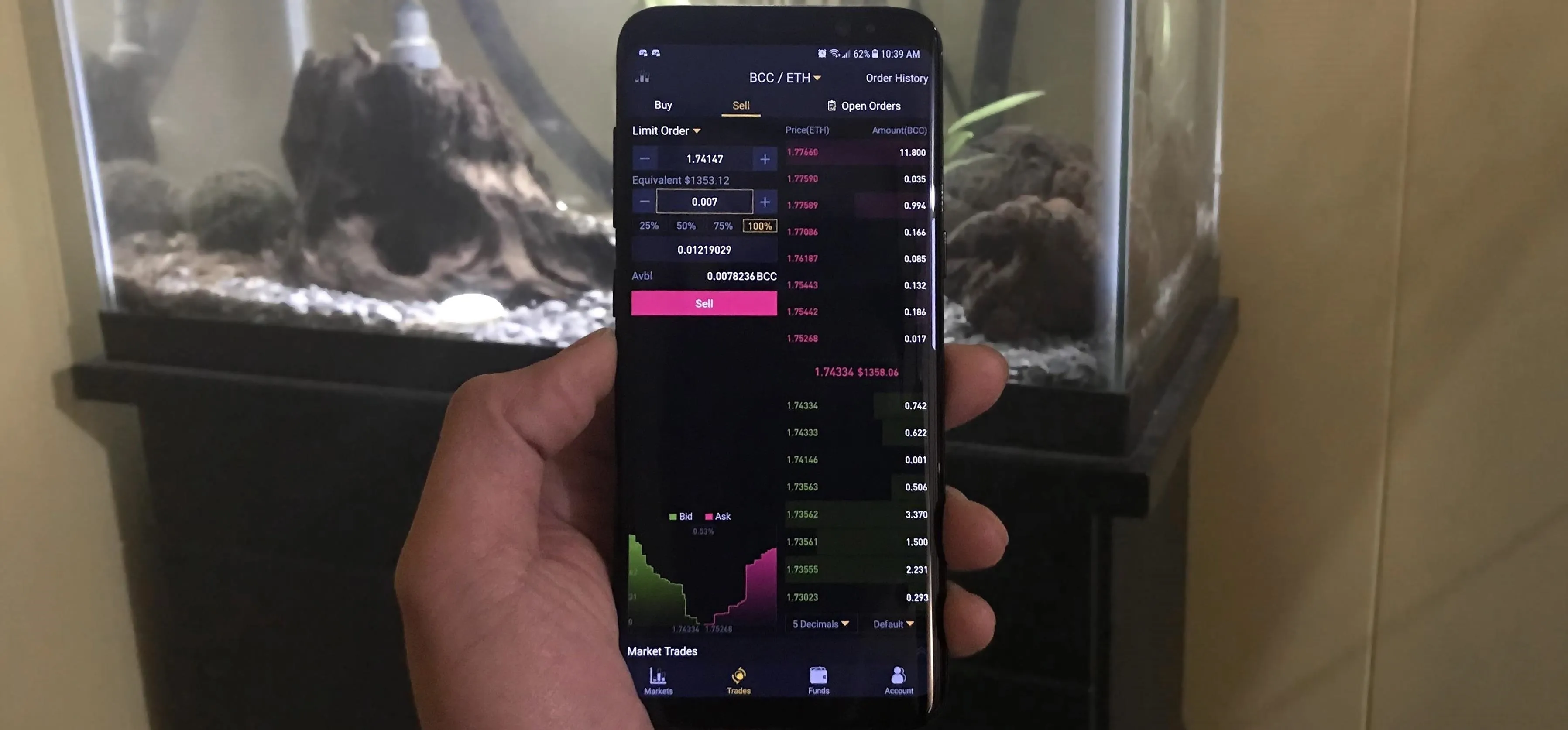 Stock market app displayed on a smartphone in front of an aquarium.