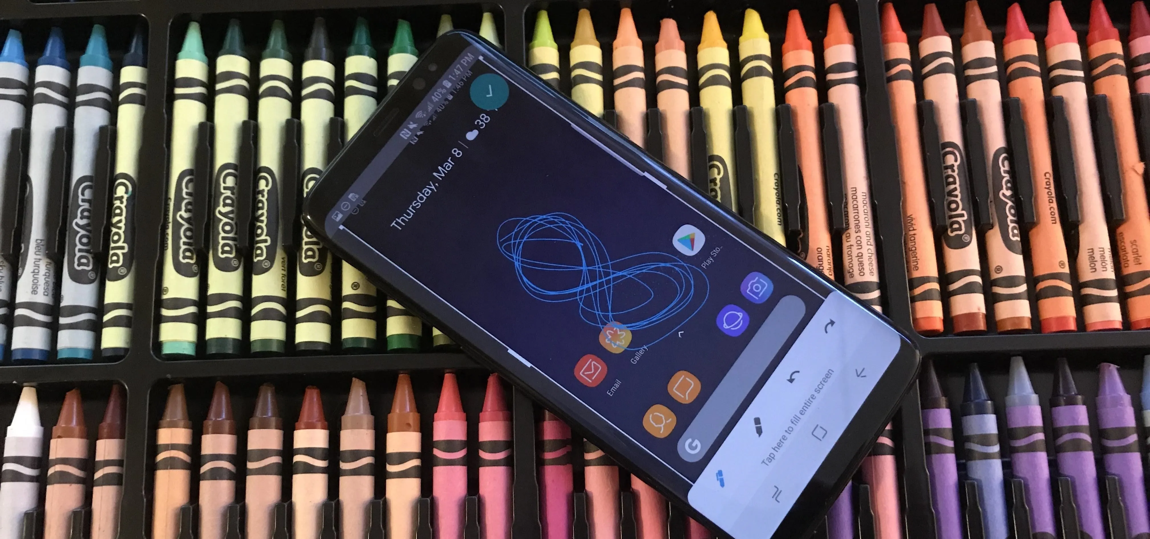 Smartphone displayed on a background of colorful crayons.