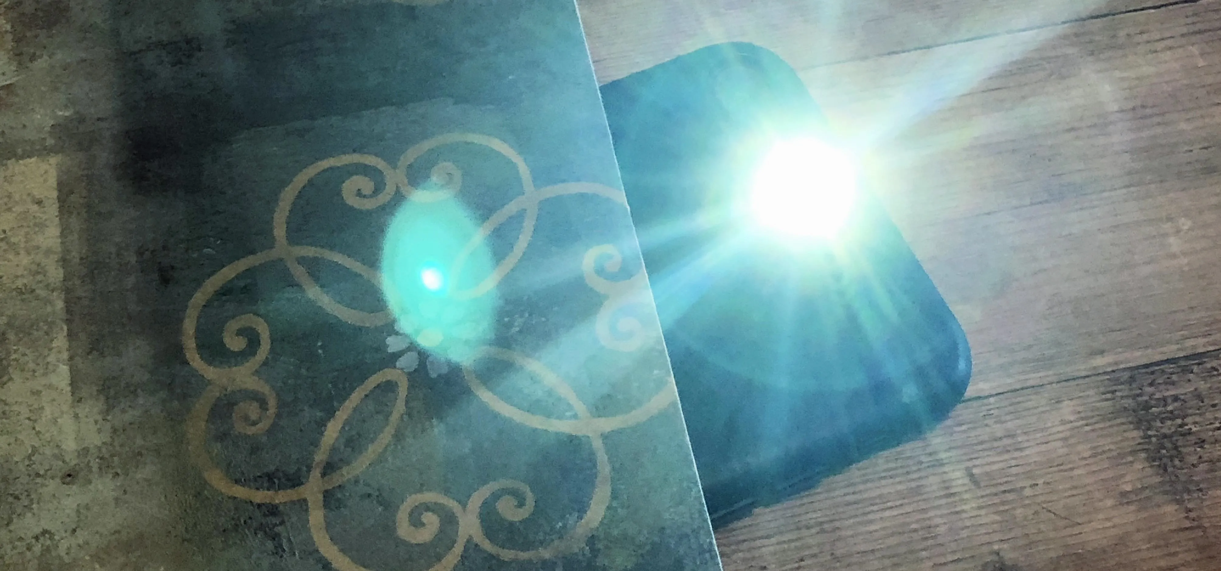 A bright light source illuminating a textured surface with a decorative pattern.