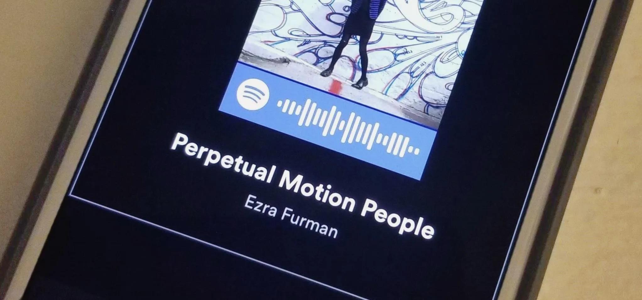 Album cover for "Perpetual Motion People" by Ezra Furman on a smartphone screen.