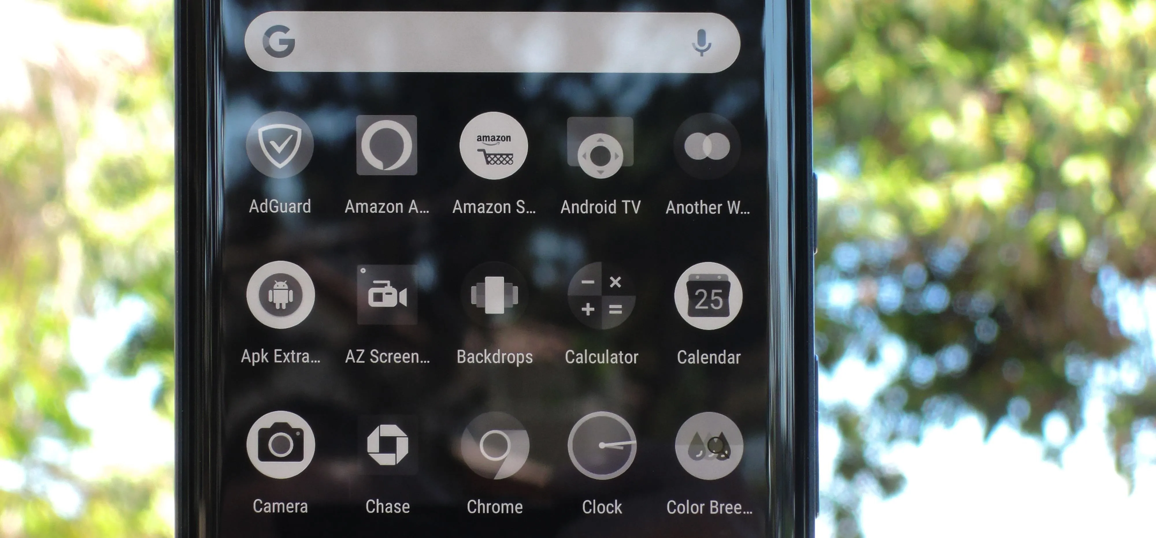 Mobile phone screen displaying various app icons and a search bar.