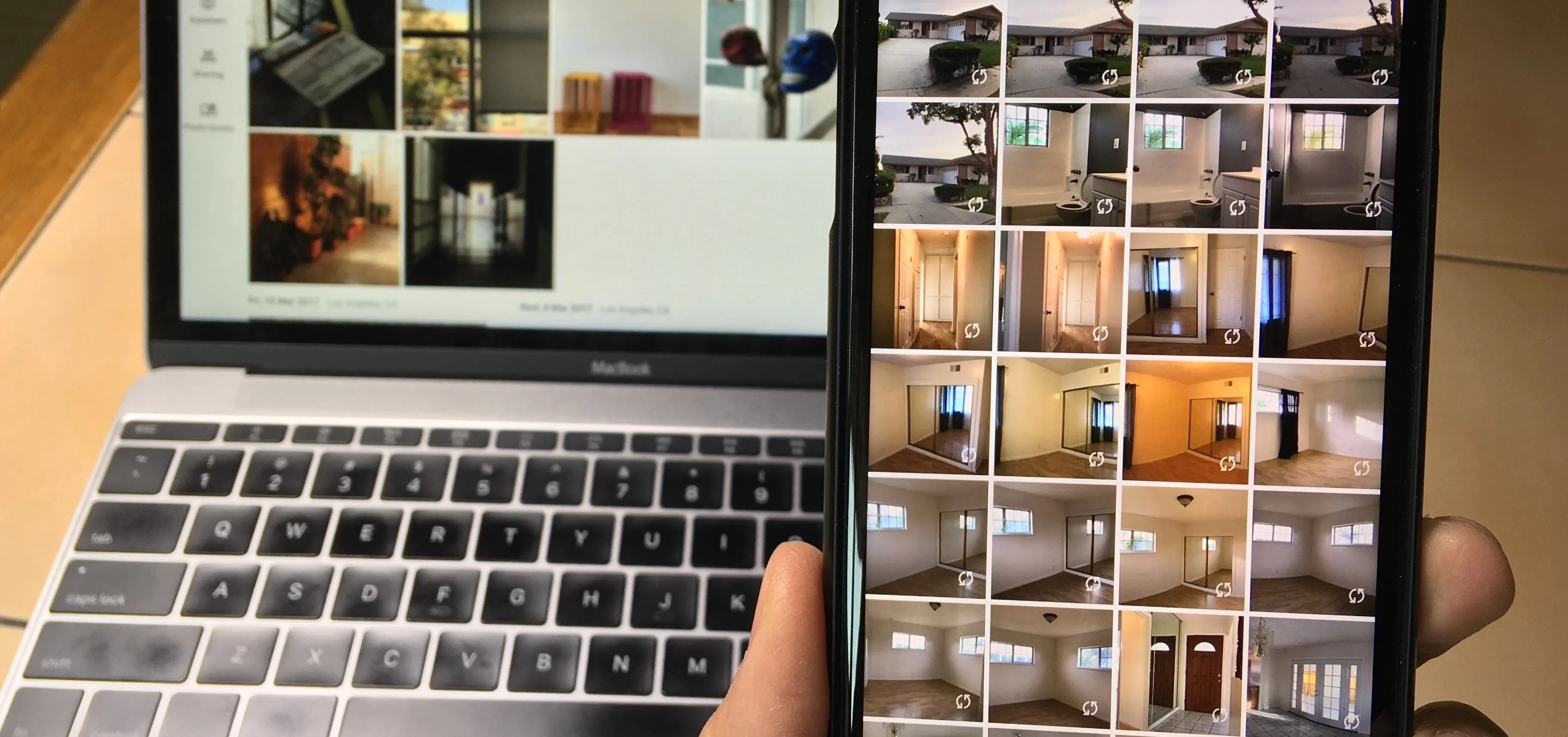 A person holding a smartphone displaying a gallery of interior photos next to a laptop showing design images.