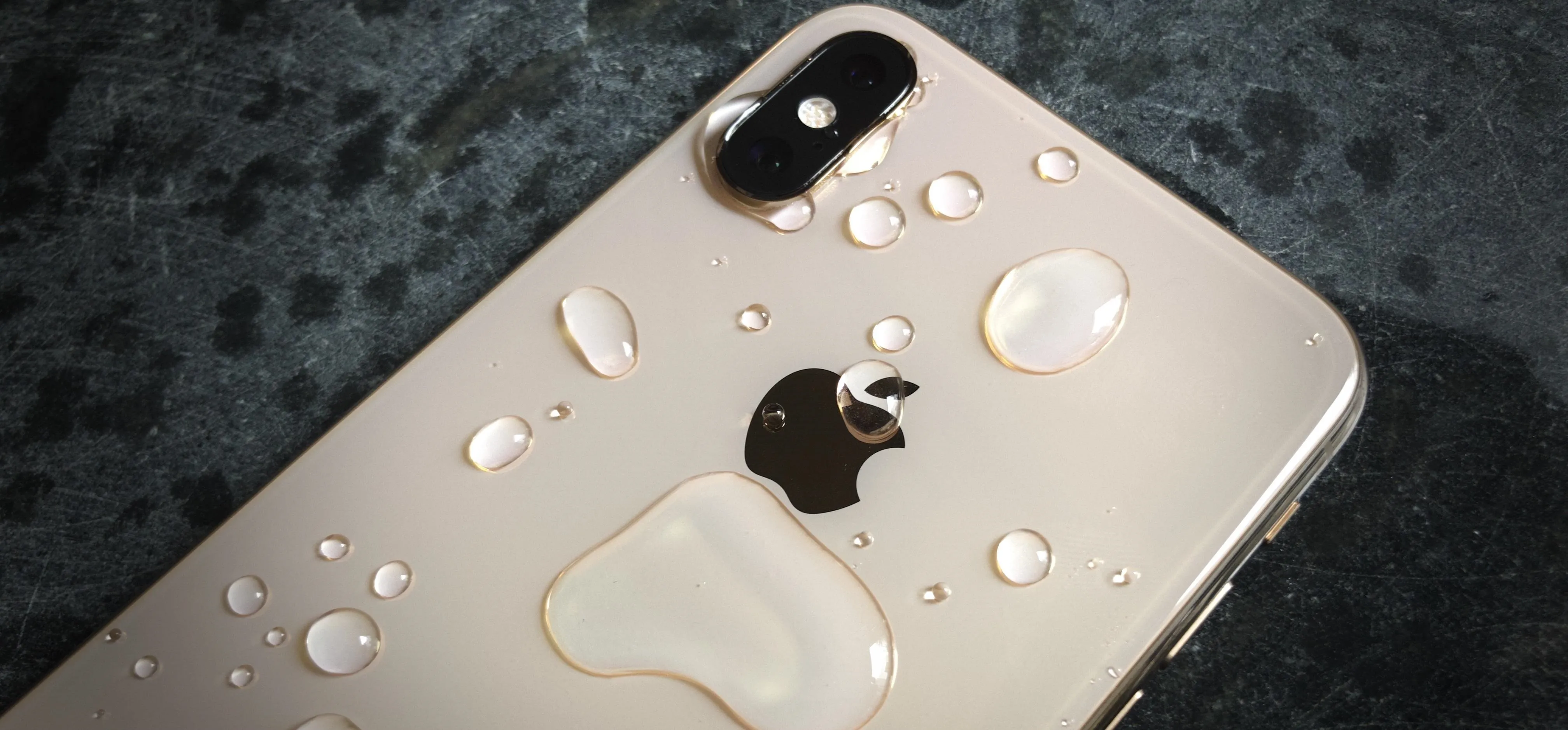 Close-up of an iPhone with water droplets on its surface.