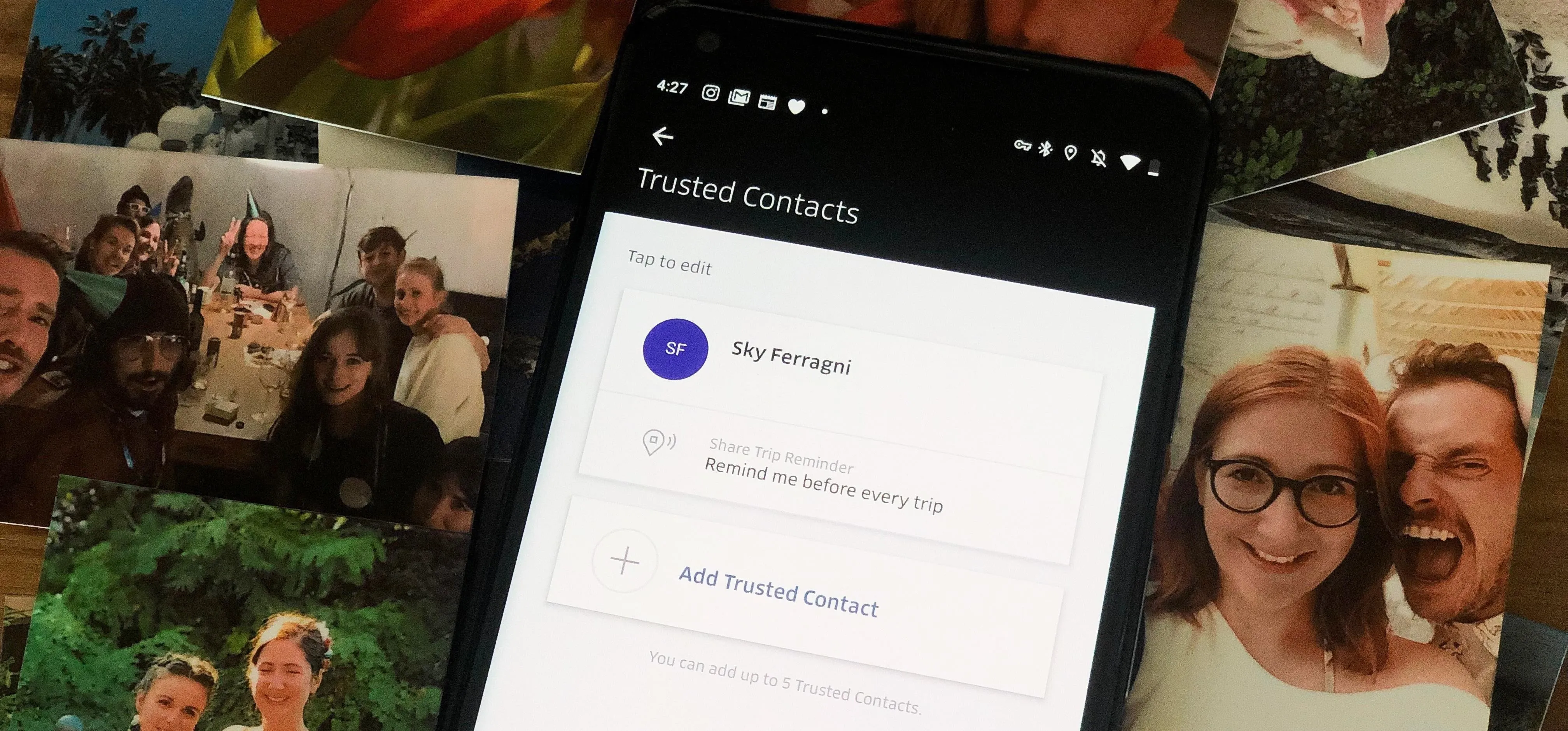 Mobile phone displaying a contact information screen surrounded by printed photos.