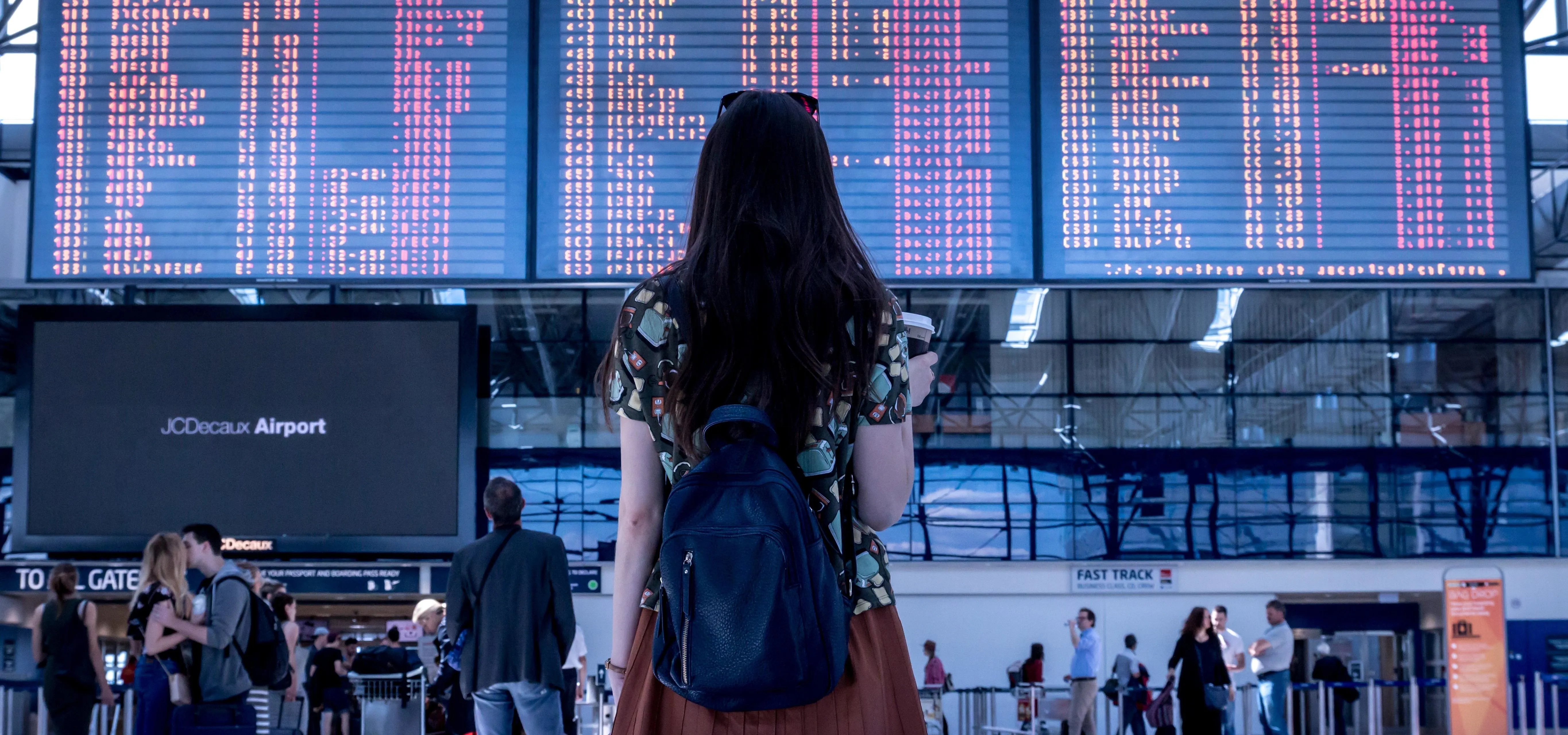 Woman looking at a flight schedule board at an airport.