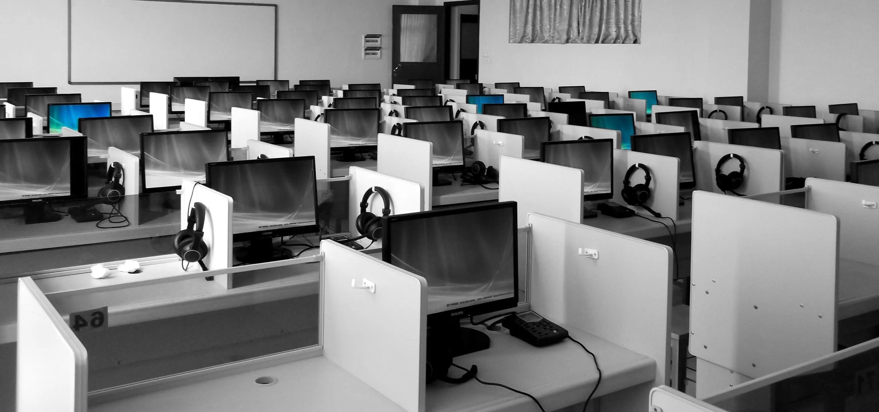 Empty computer lab with multiple workstations and headsets.