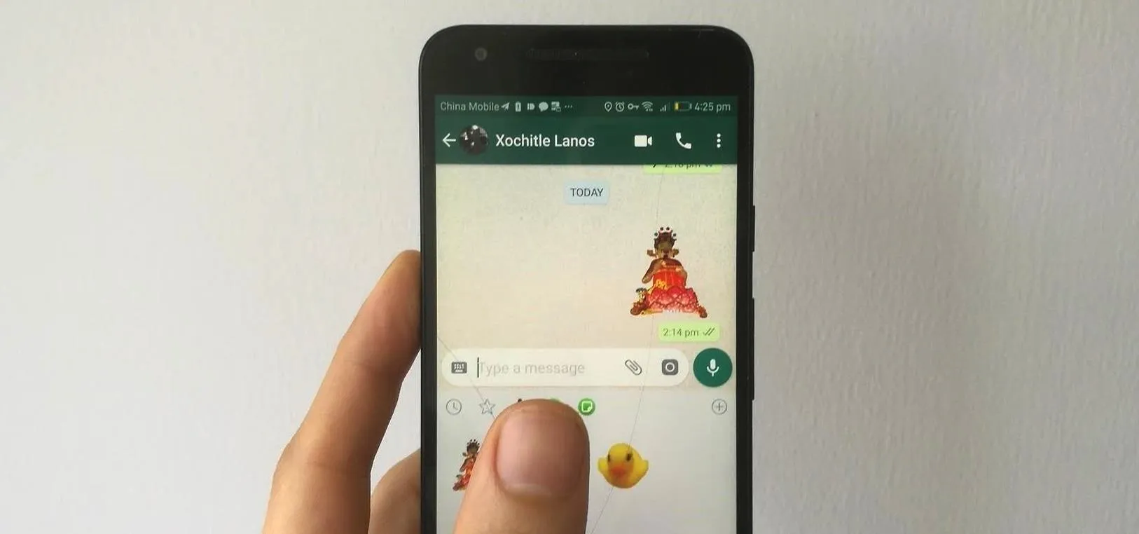 Hand holding a smartphone displaying a chat in a messaging app.