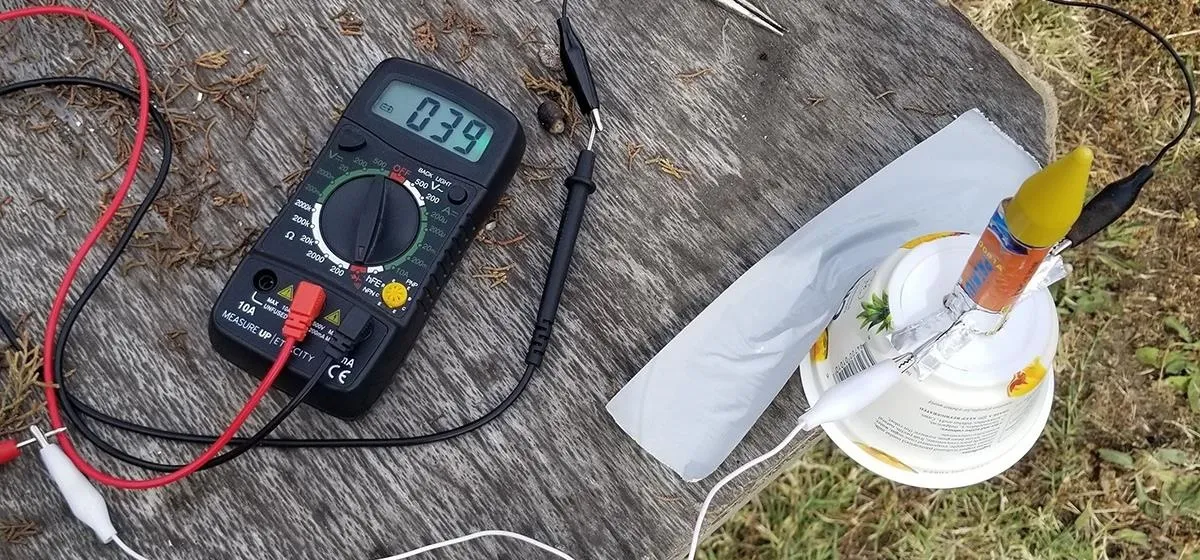 Digital multimeter measuring voltage next to a DIY electrical project.