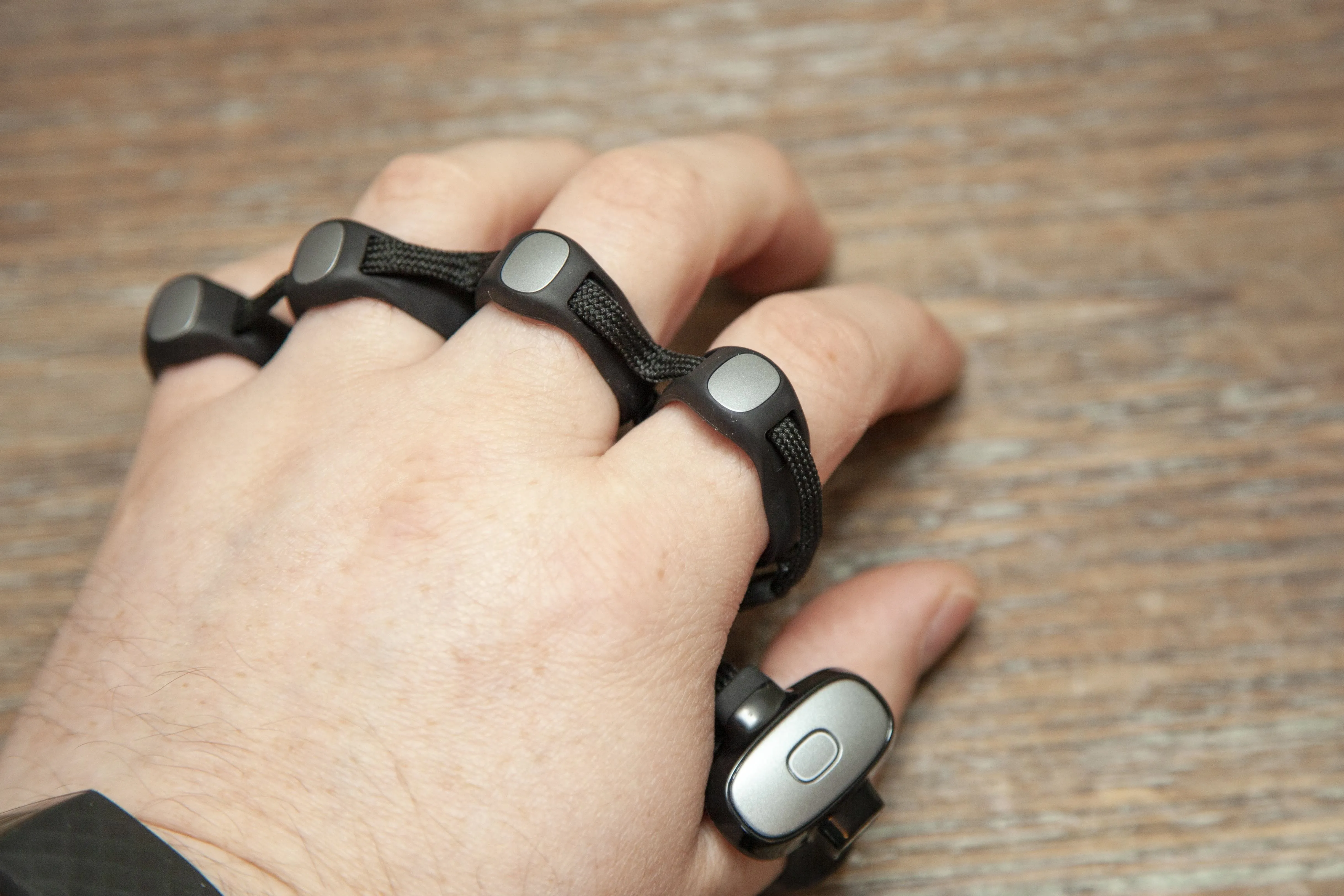 A hand wearing a device with buttons on each finger.