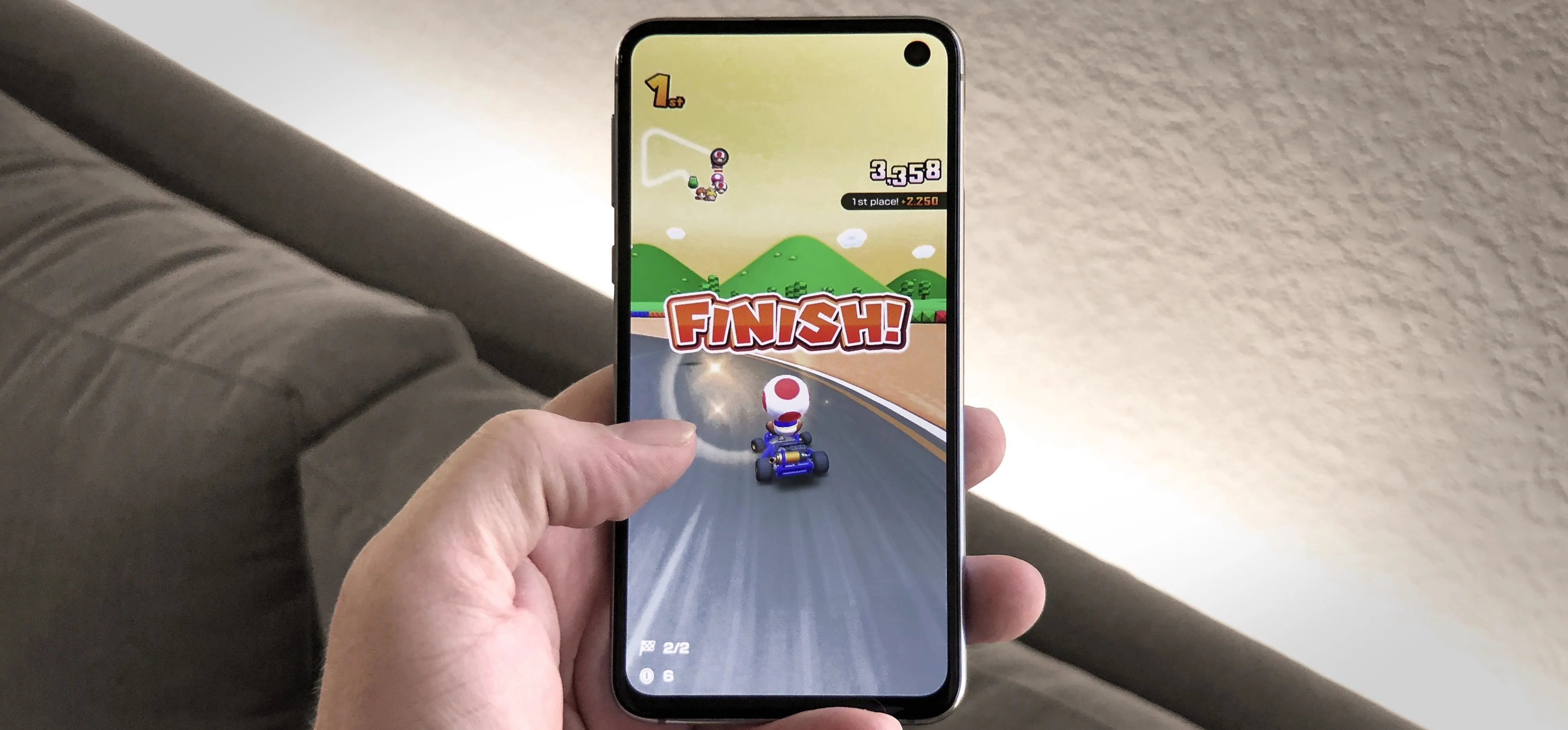 Person playing a racing game on a smartphone, showing the "FINISH" screen.