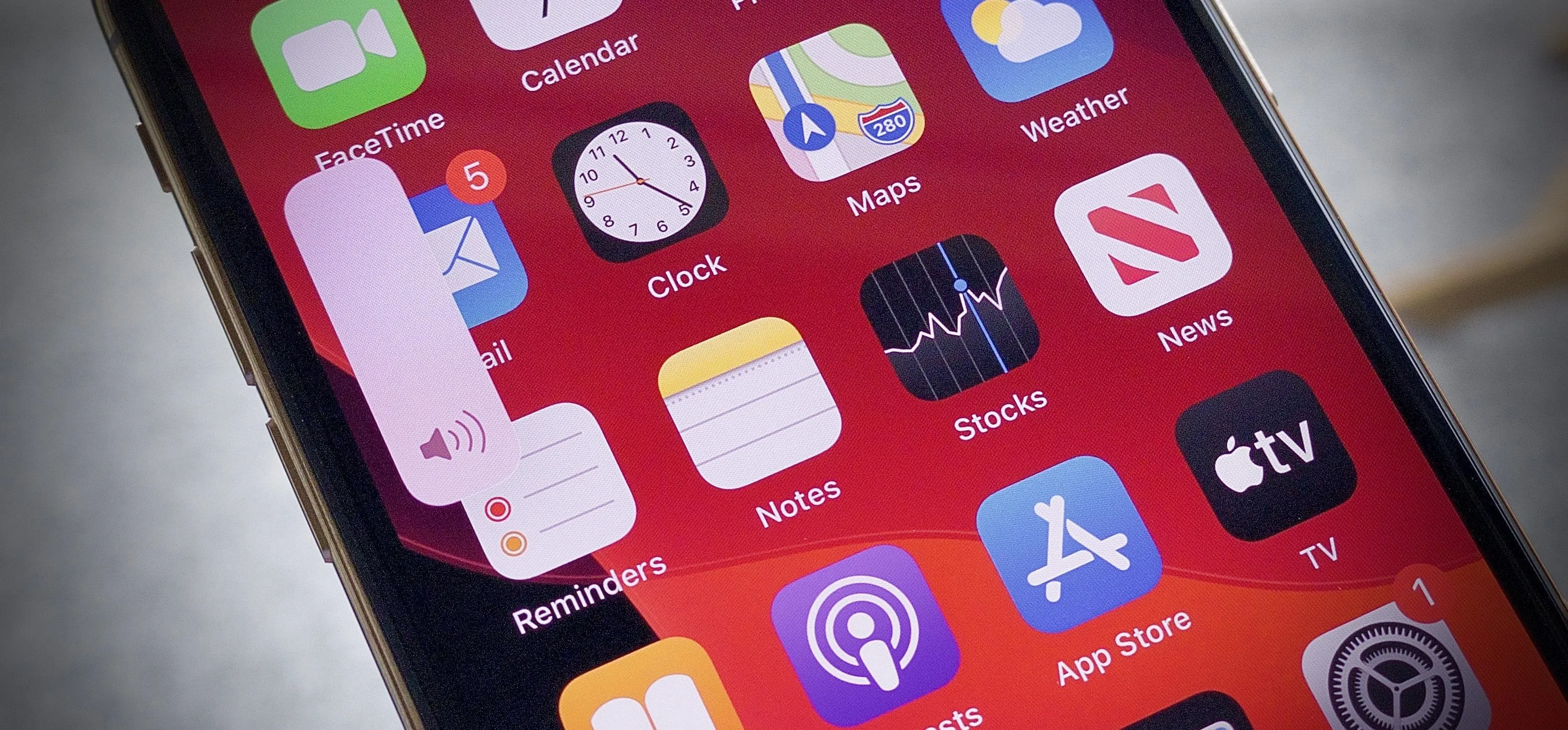 Smartphone screen displaying various app icons on a red background.