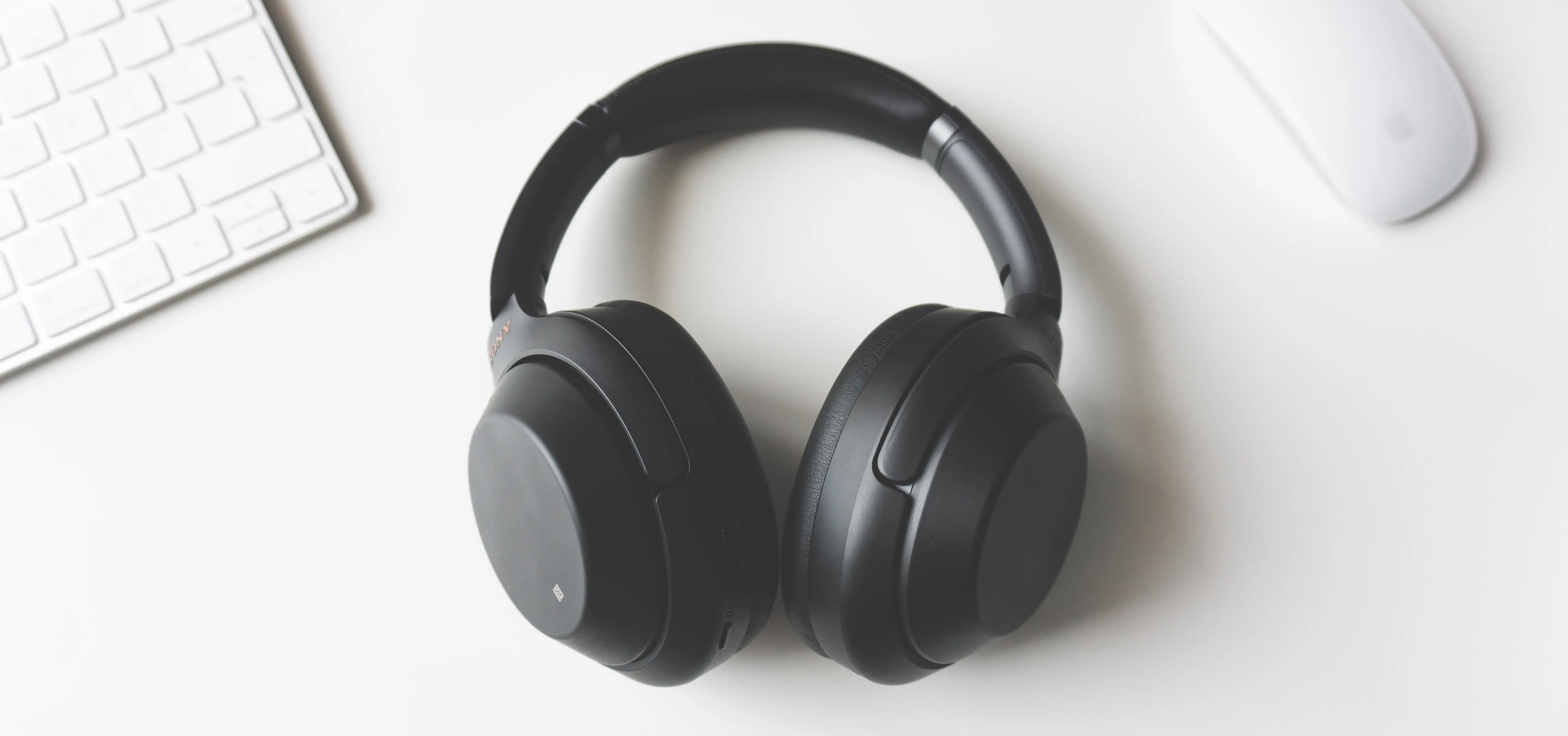 Wireless black headphones on a white desk.