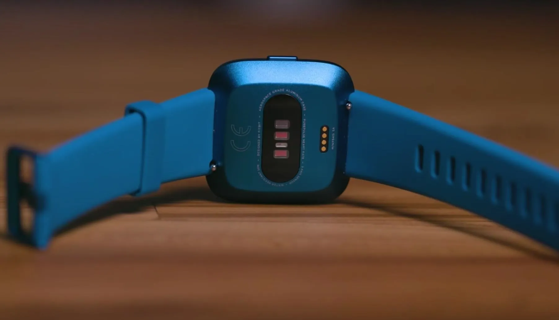 Smartwatch with a blue strap, displayed from a rear angle.