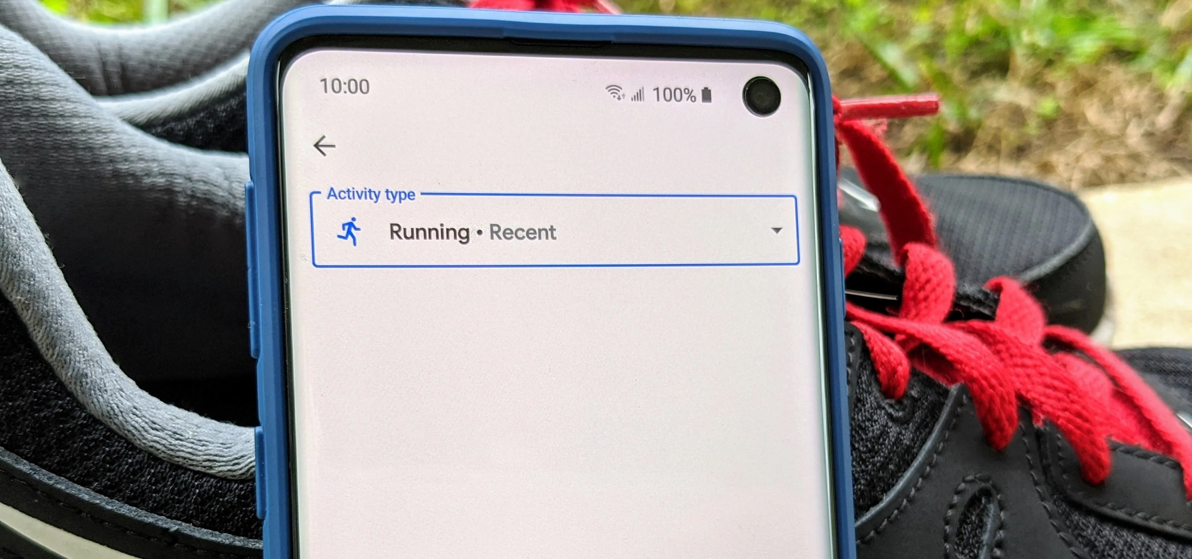 Mobile phone displaying a running record option, placed near athletic shoes.