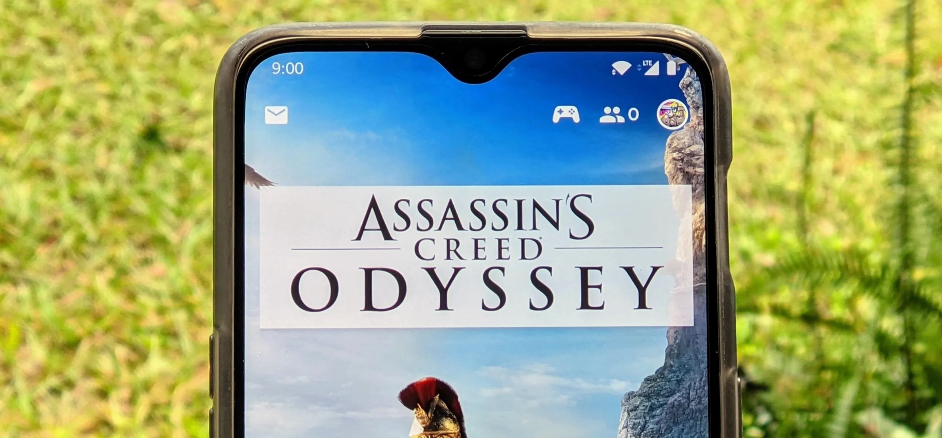 Assassin's Creed Odyssey displayed on a smartphone screen outdoors.