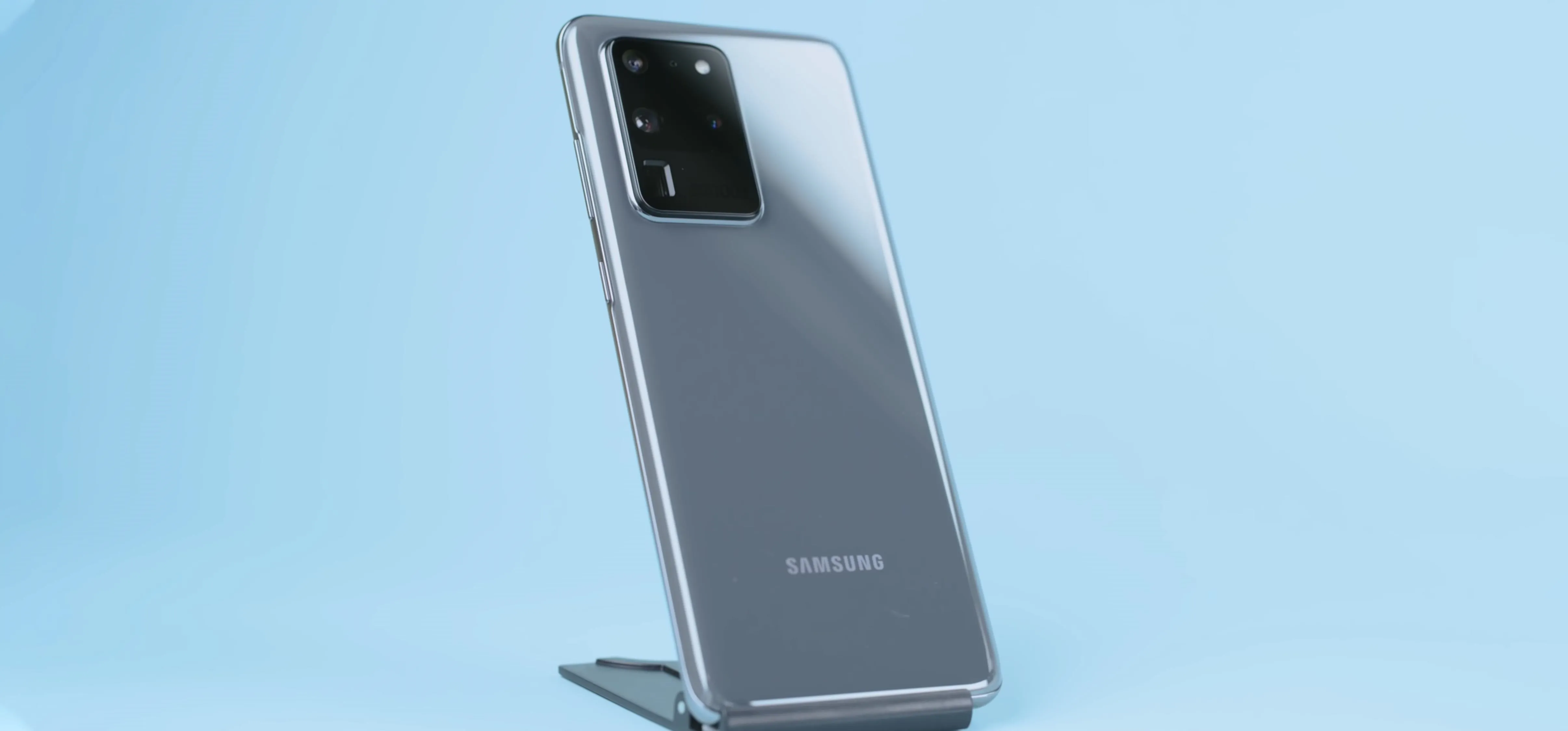 Samsung smartphone on a stand with a light blue background.