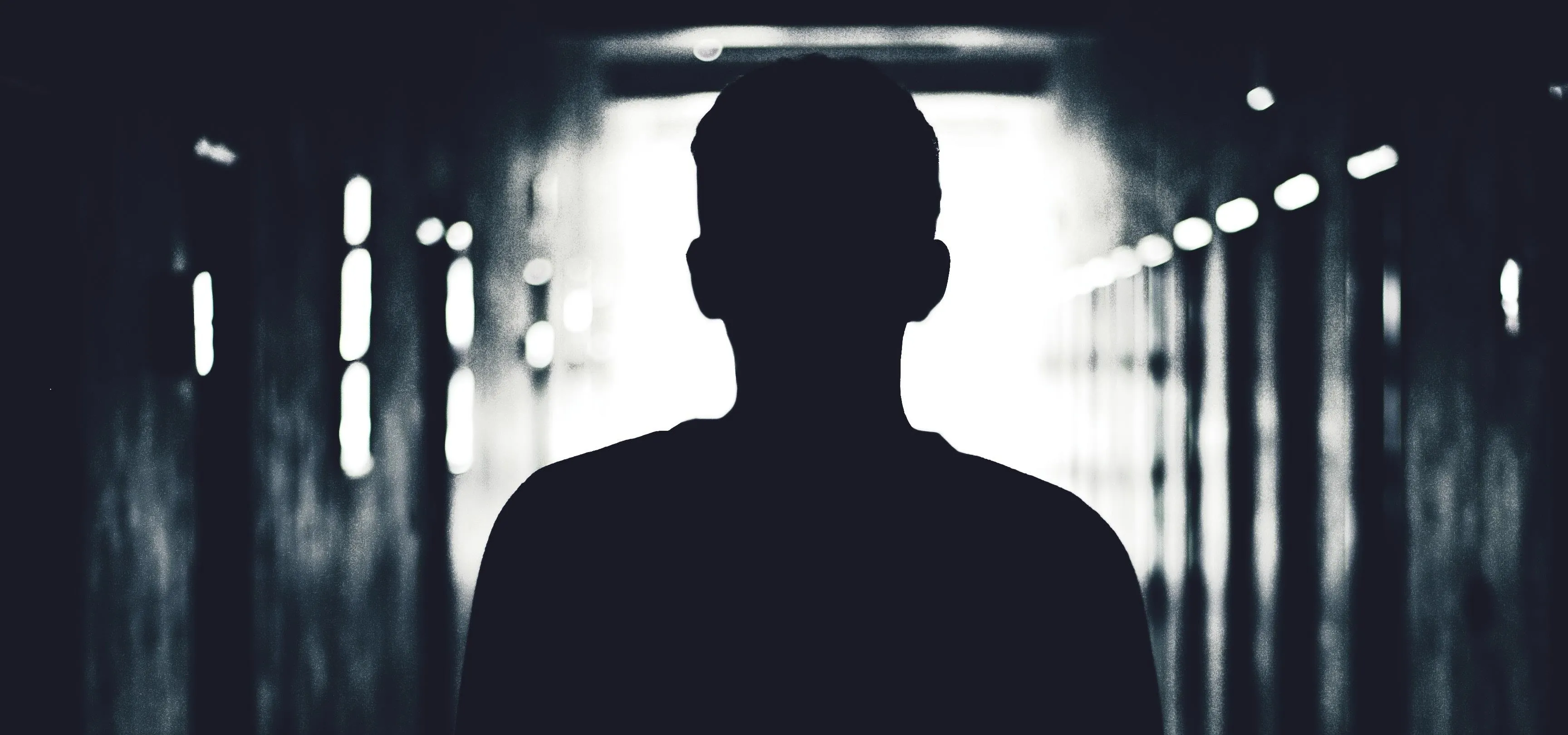 Silhouette of a person standing in a dimly lit corridor.
