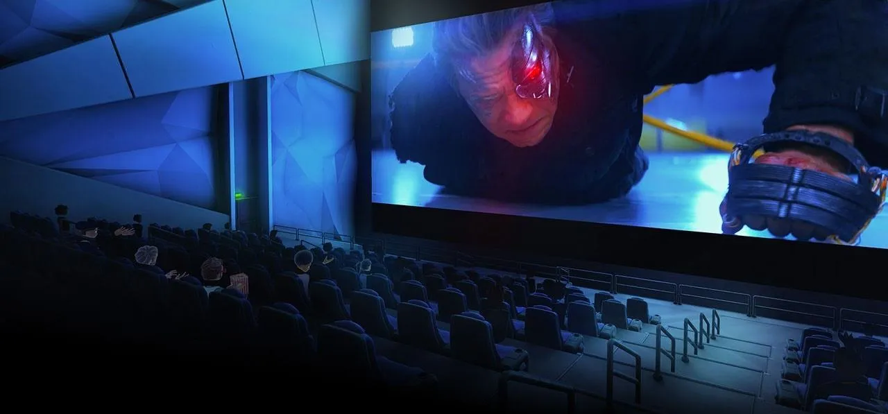 A film scene projected on a large screen in a modern theater with empty seats.