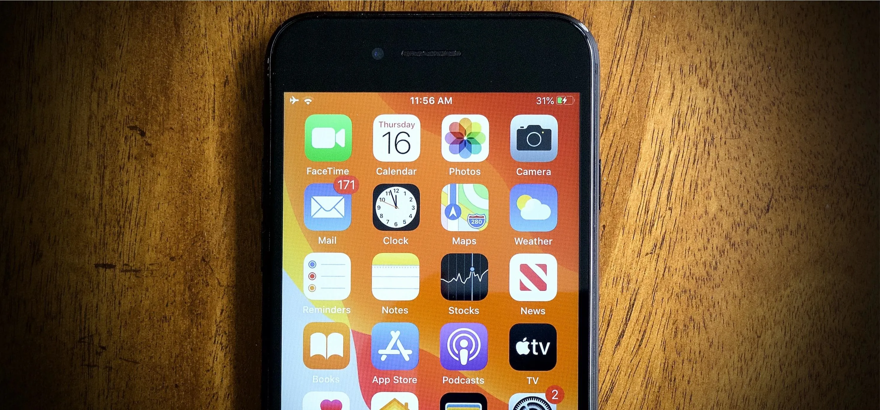 Smartphone screen showing various app icons on a wooden surface.