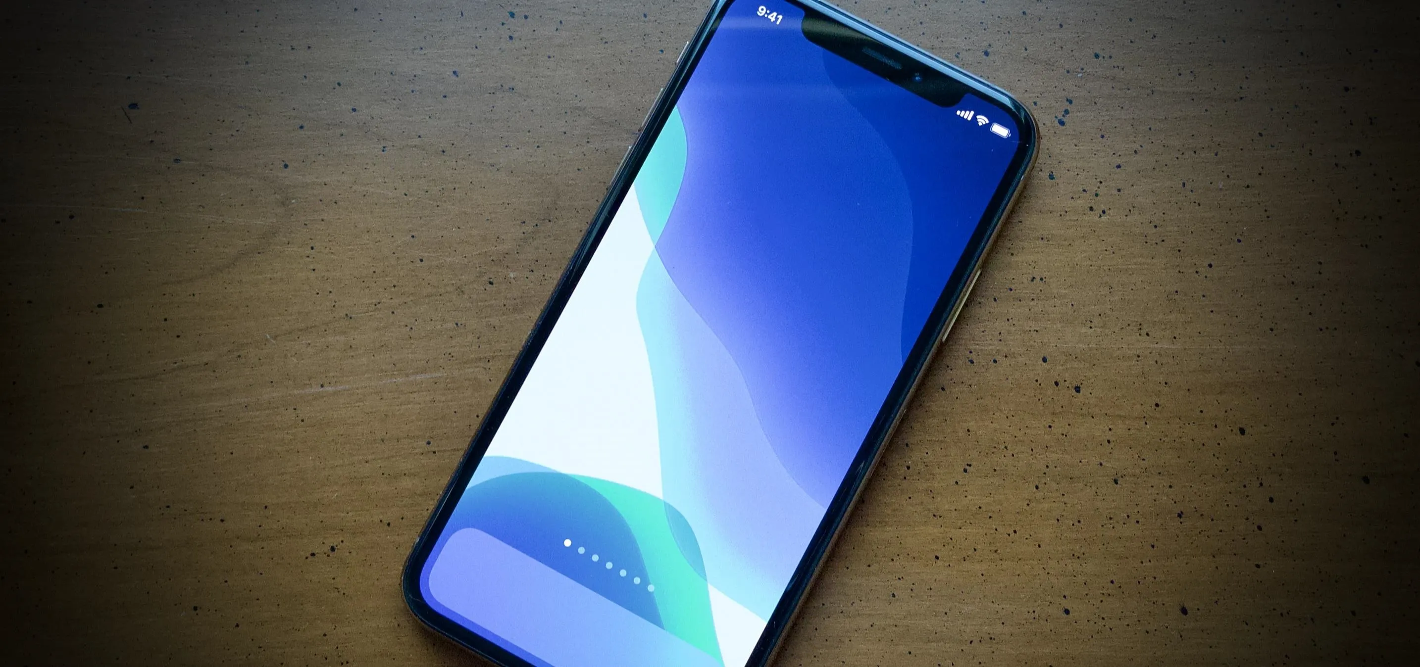 Smartphone lying on a wooden surface with a blue display.