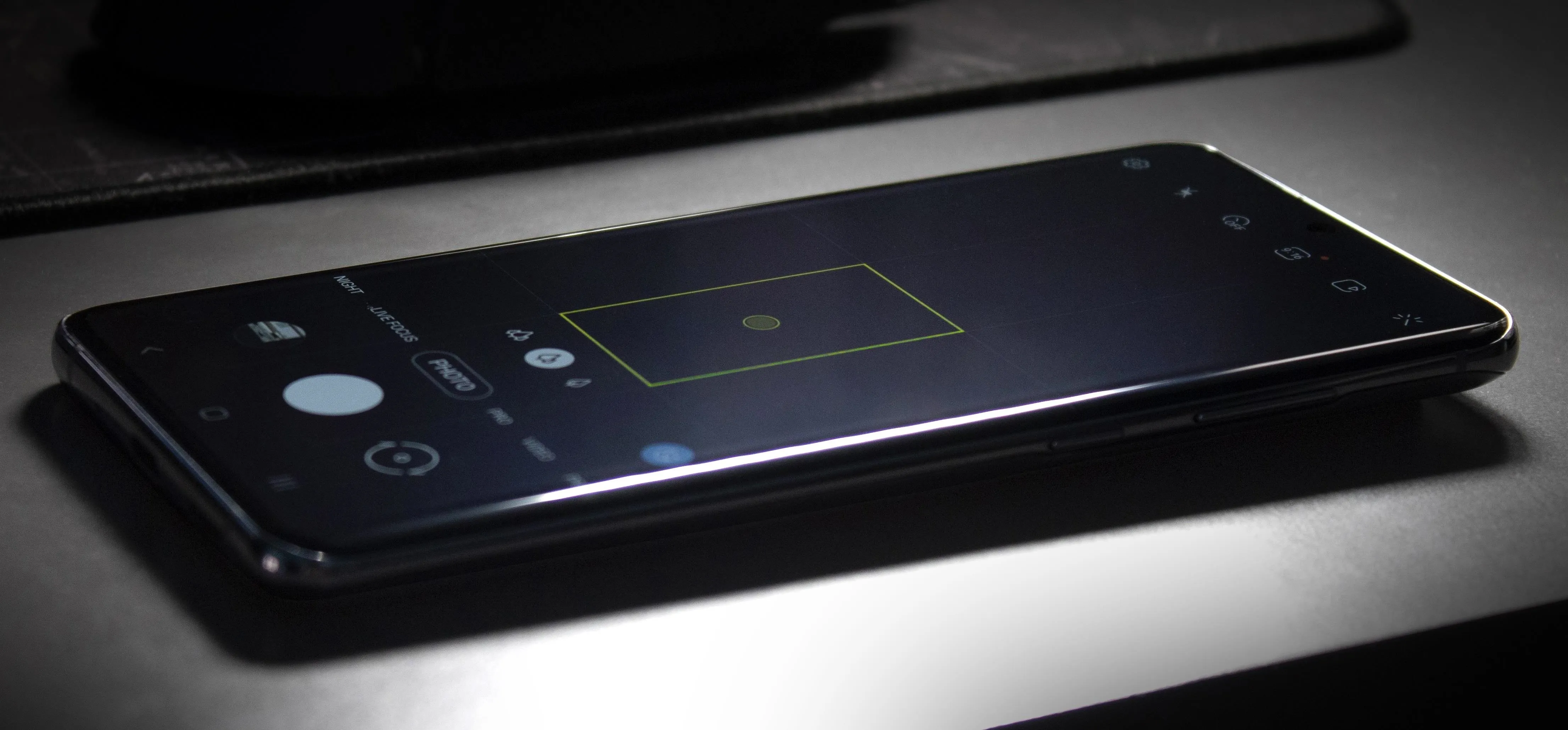 Smartphone displaying a camera interface on a dark surface.