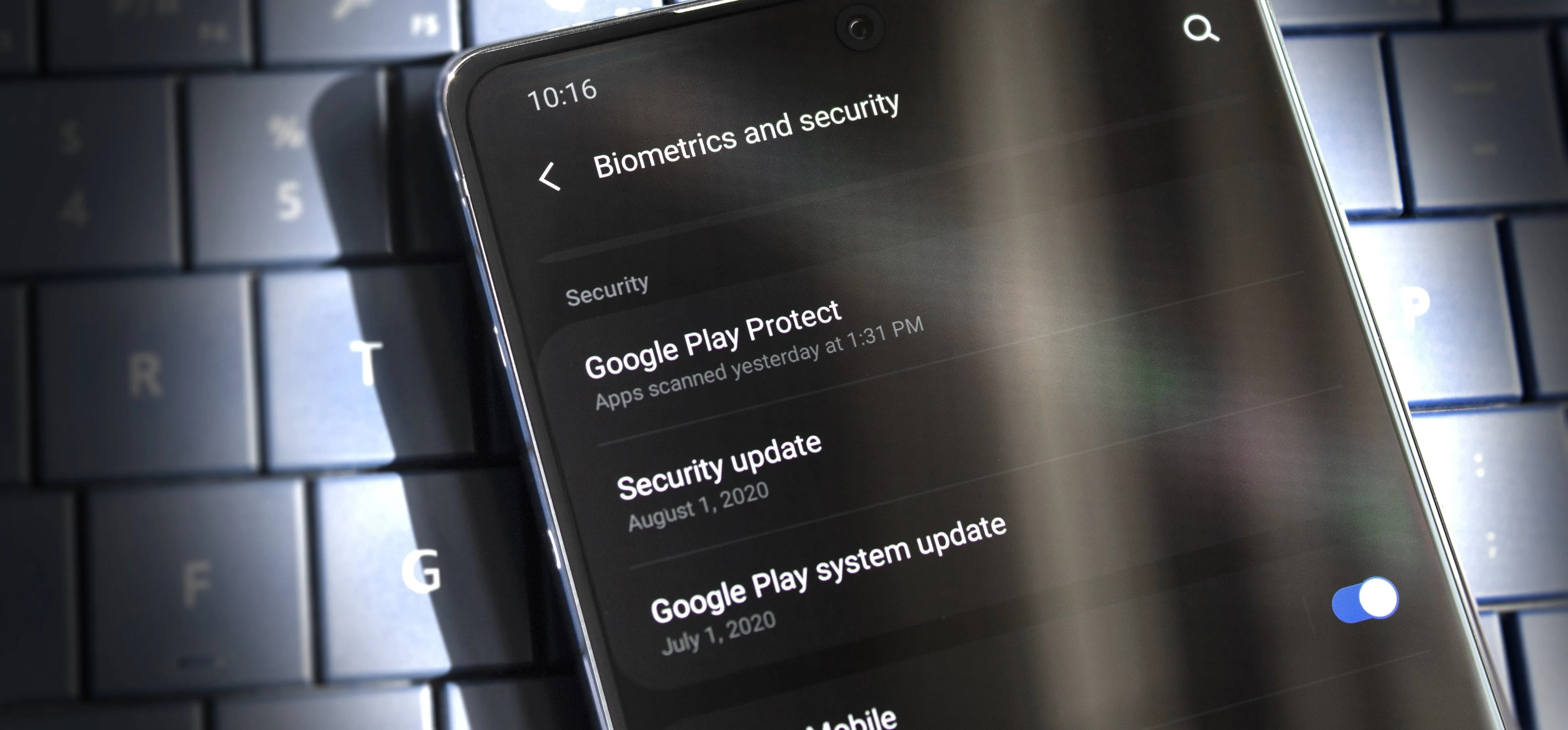 Smartphone screen displaying security settings and updates on a keyboard background.