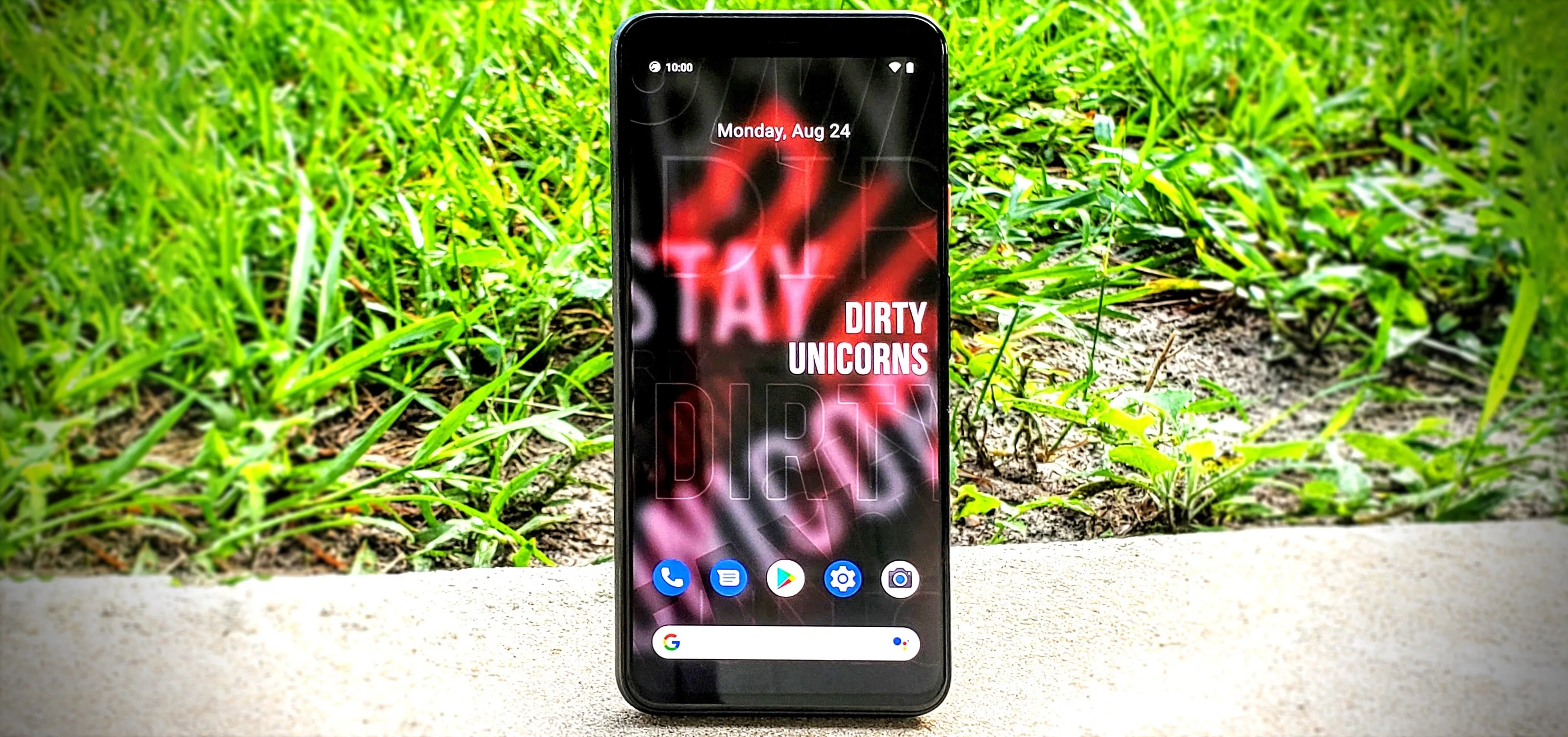 Smartphone displaying a colorful wallpaper on a grassy surface.