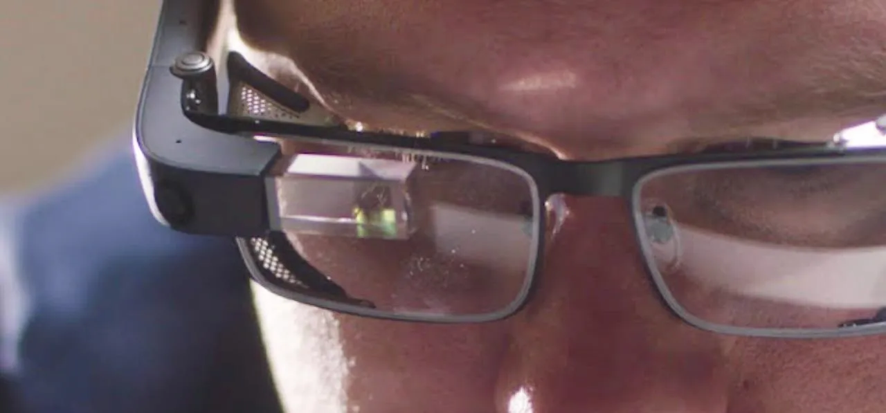 Close-up of a person's face wearing glasses with a reflection in the lenses.